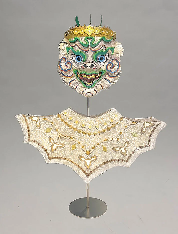 This piece is a paper-cut bust of Hanuman, a prominent figure in Cambodian mythology and performance traditions. Inspired by Cambodian masked theater known as Lakhon Khol, the design draws from its stylized forms and expressive visual language. Throu