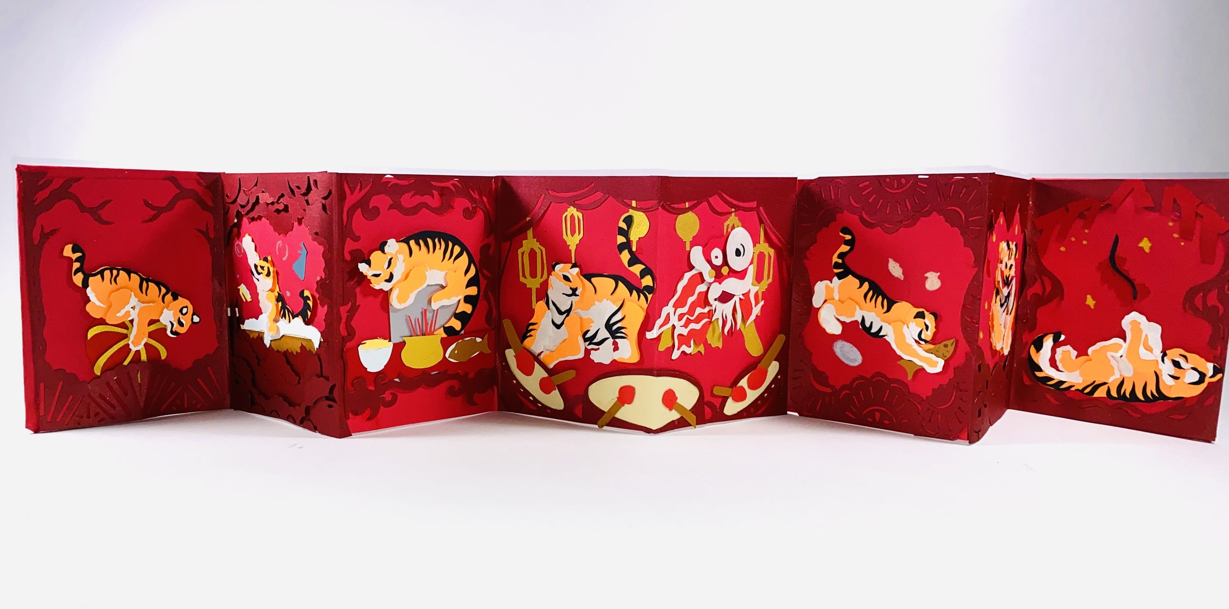 This paper-cut accordion book depicts a tiger participating in the traditional preparations and celebrations of Lunar New Year. As the pages unfold, the tiger moves through different moments of the holiday, reflecting the rituals and joy that surroun