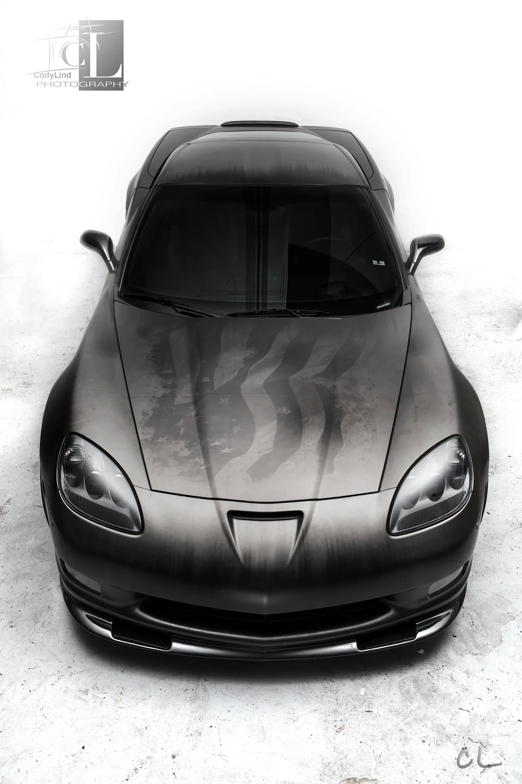Overhead view of a black sports car with a custom paint job featuring American flag stripes on the hood.