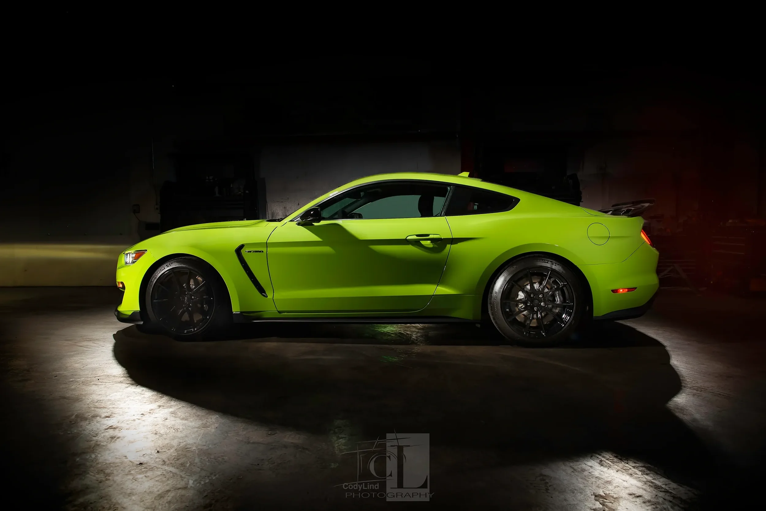 A bright green sports car parked indoors with dramatic lighting and shadows.