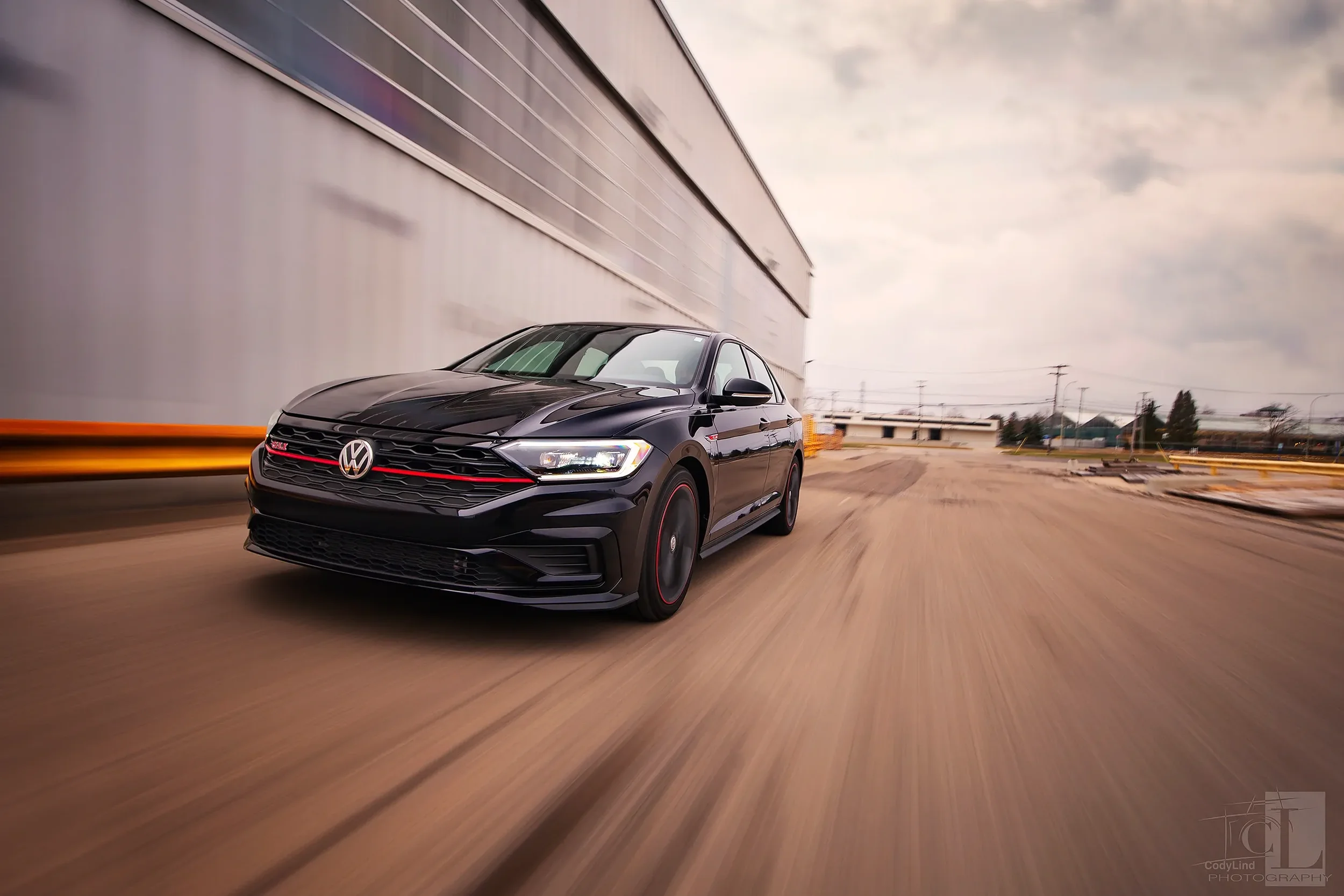 A black Volkswagen sedan driving at high speed on an empty street with motion blur.