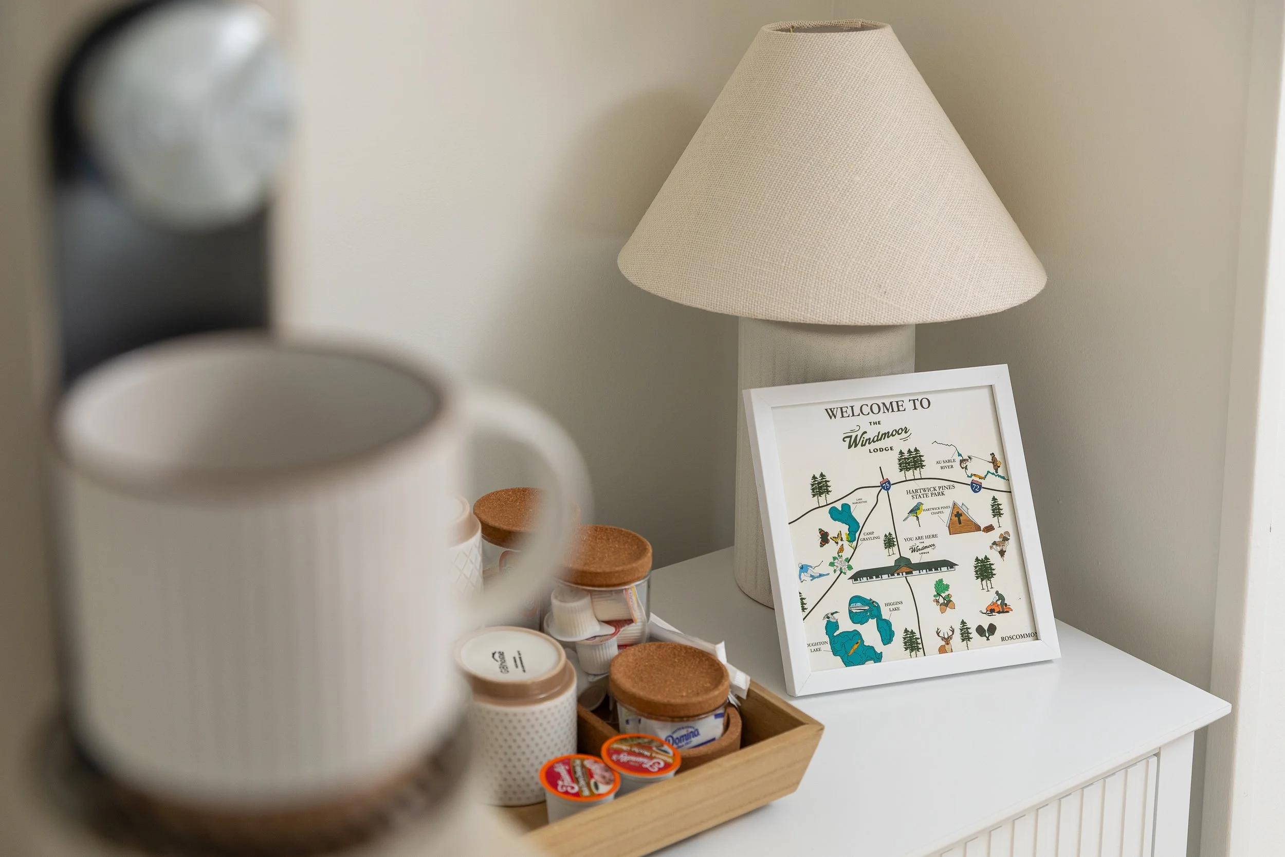 A table with a framed map and a lamp, with coffee cups and creamer containers in the foreground.
