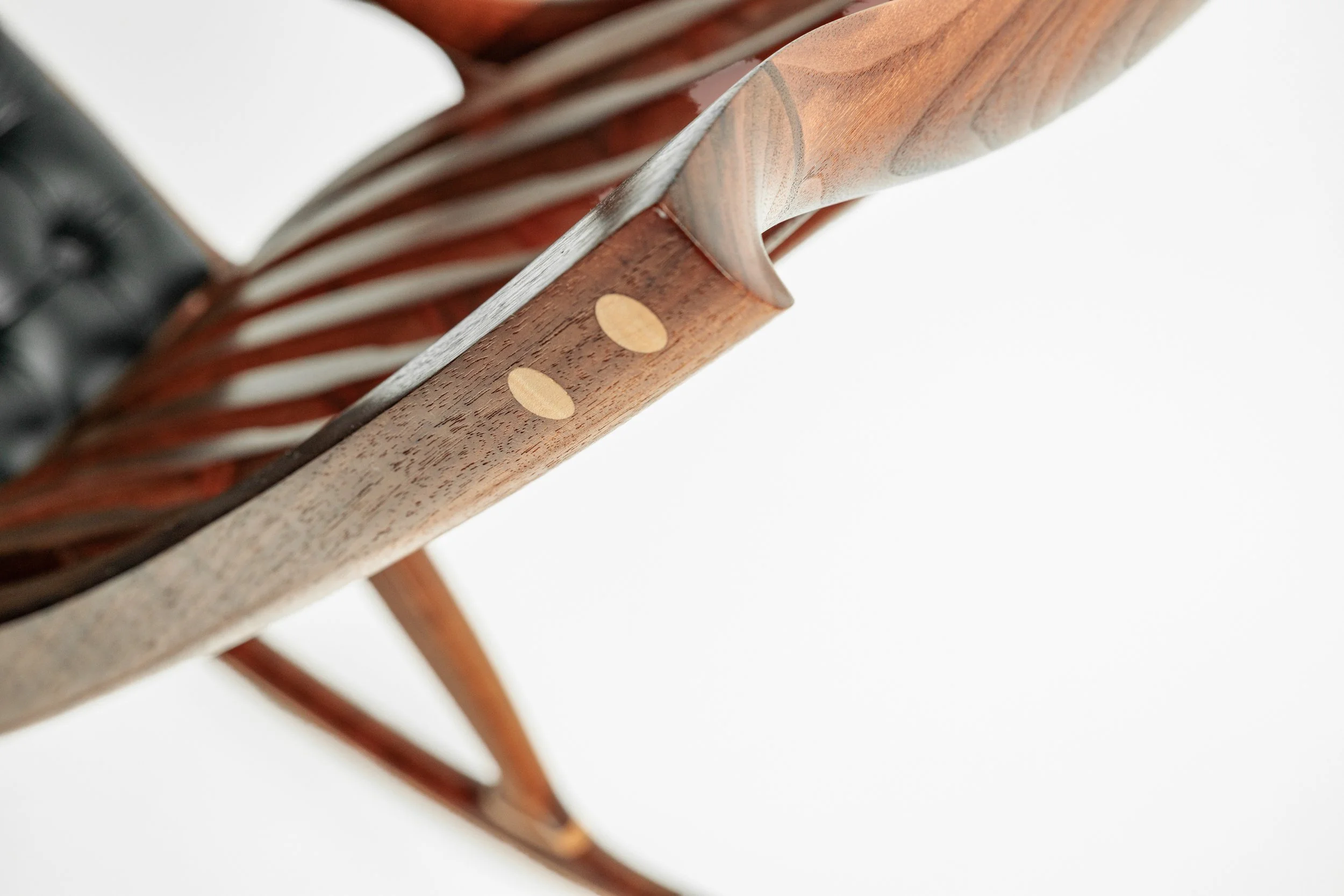 Close-up image of a wooden chair with a woven backrest, showing detailed craftsmanship and a smooth finish.