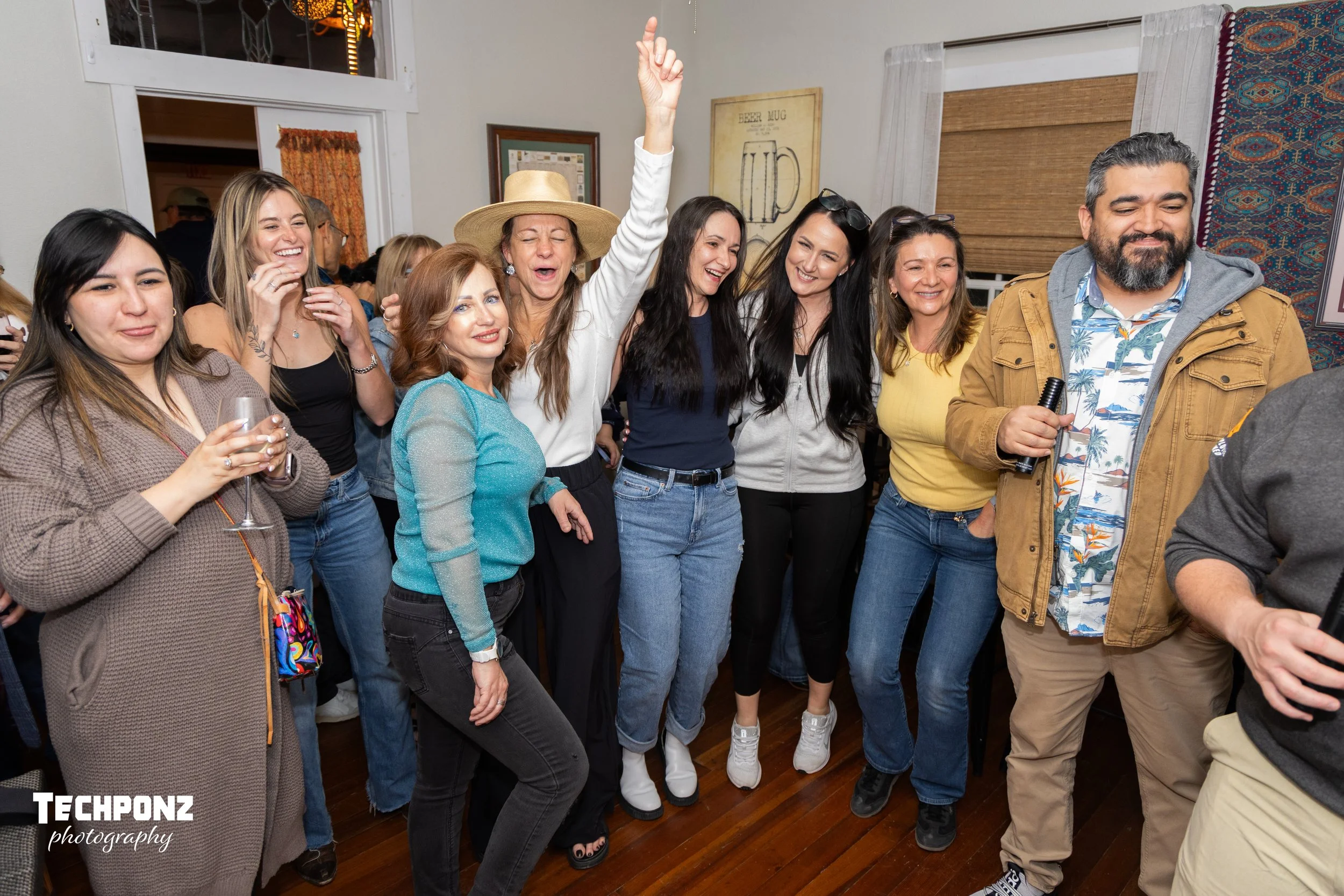 A group of people dancing and enjoying themselves at a party or celebration in a cozy indoor setting.