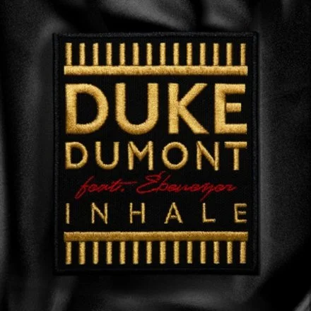 A fabric patch with the name 'Duke Dumont' in gold, and the words 'feat. Ebenezer Inhale' in red and gold, with a black background and gold borders.