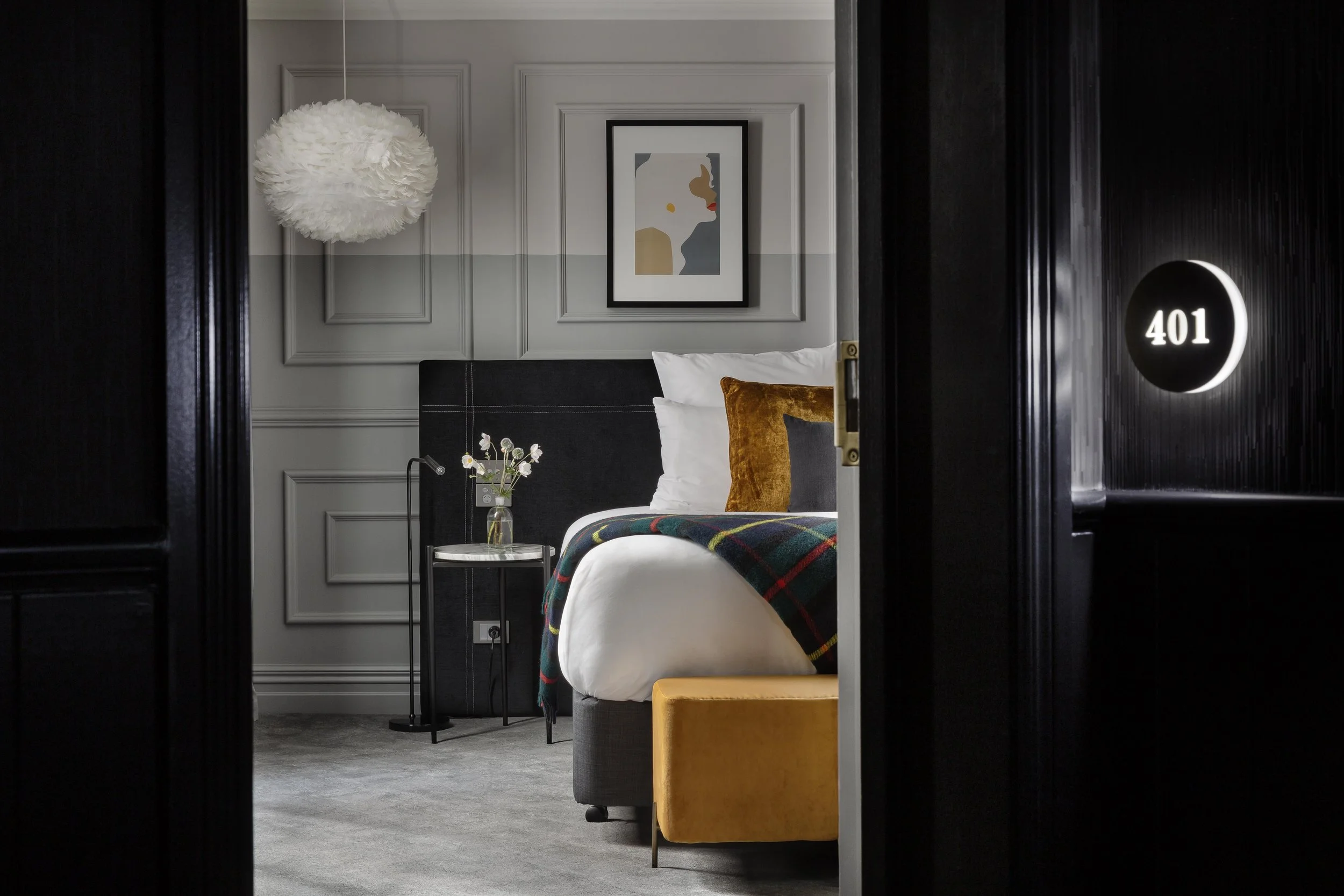 Hotel room with a bed, soft lighting, framed art, and a room number sign reading 401.