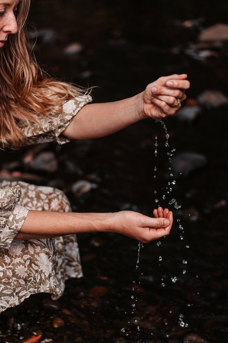 Woman connecting with water in nature, symbolising healing, balance and Ayurveda practices in Currumbin Valley
