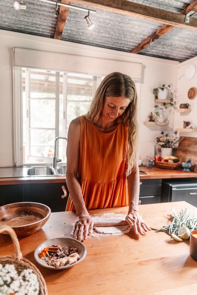 Woman preparing food with herbs in a kitchen, reflecting Ayurvedic nutrition and holistic living on the Gold Coast