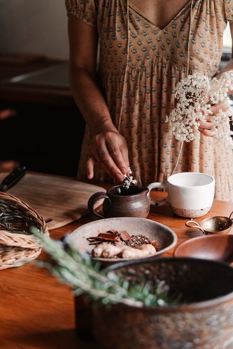 Woman arranging flowers and tea, representing calm rituals, nervous system support and Ayurveda lifestyle Gold Coast