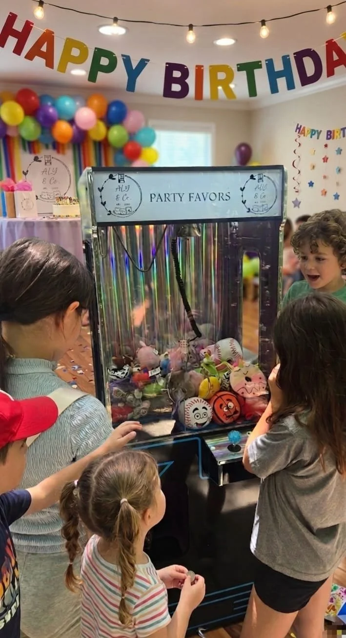 A group of kids using one of the claw machines at a party.