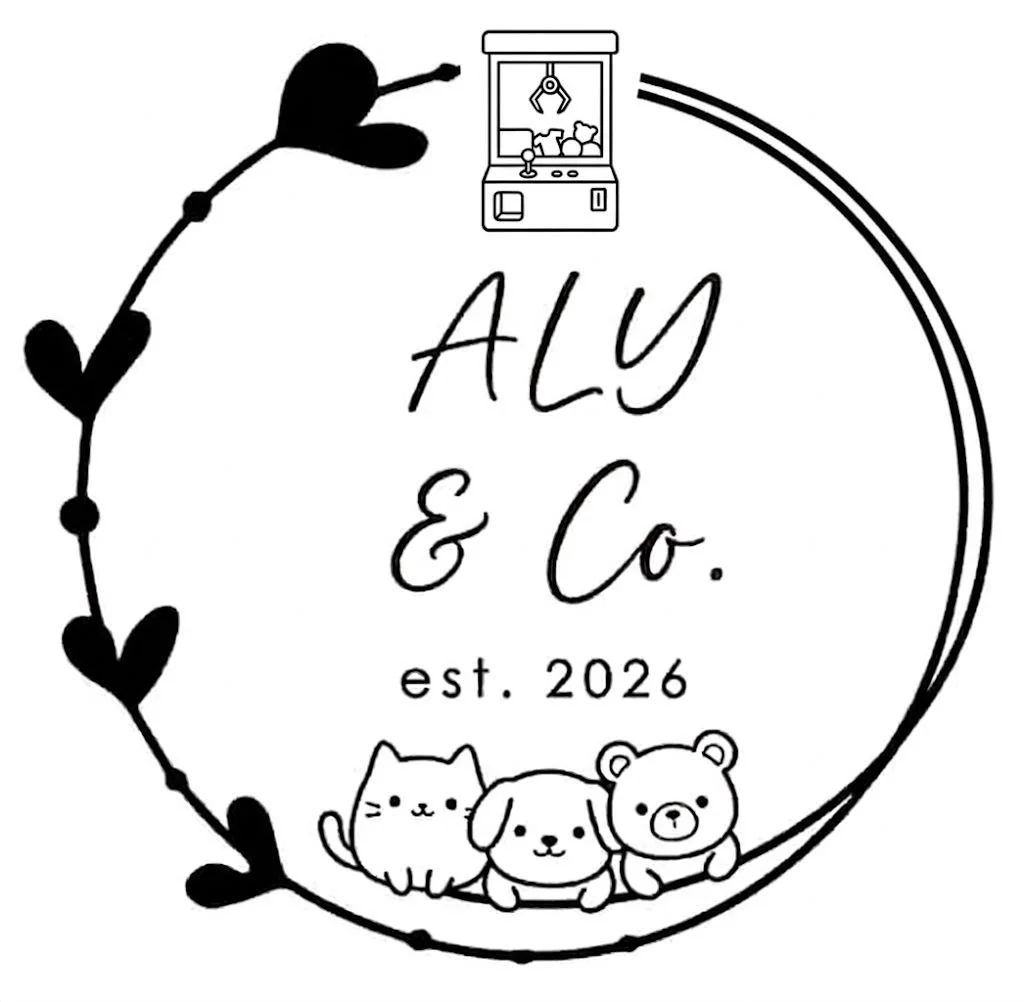 A circular logo with a hand-drawn style featuring a cat, a puppy, and a bear at the bottom. The logo includes the text 'ALY & Co.' and 'est. 2026' in the center, with a small vending machine at the top and a decorated border of black hearts around the circle.