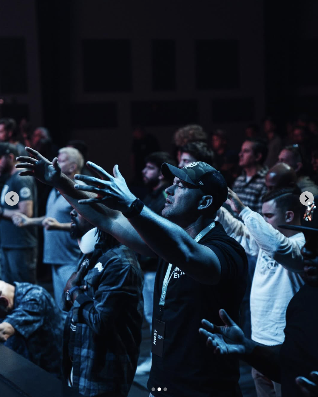Photo of men worshiping at a men's event, highly contrasted in blue light. Photo by Baylee Perry.