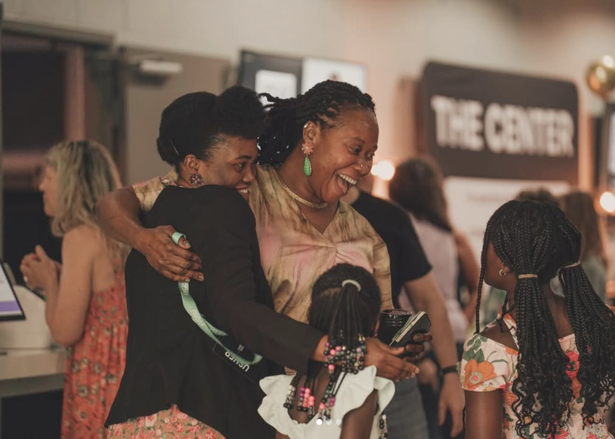 Photo of two women smiling brightly on a Sunday morning with their children. Taken by Baylee Perry.