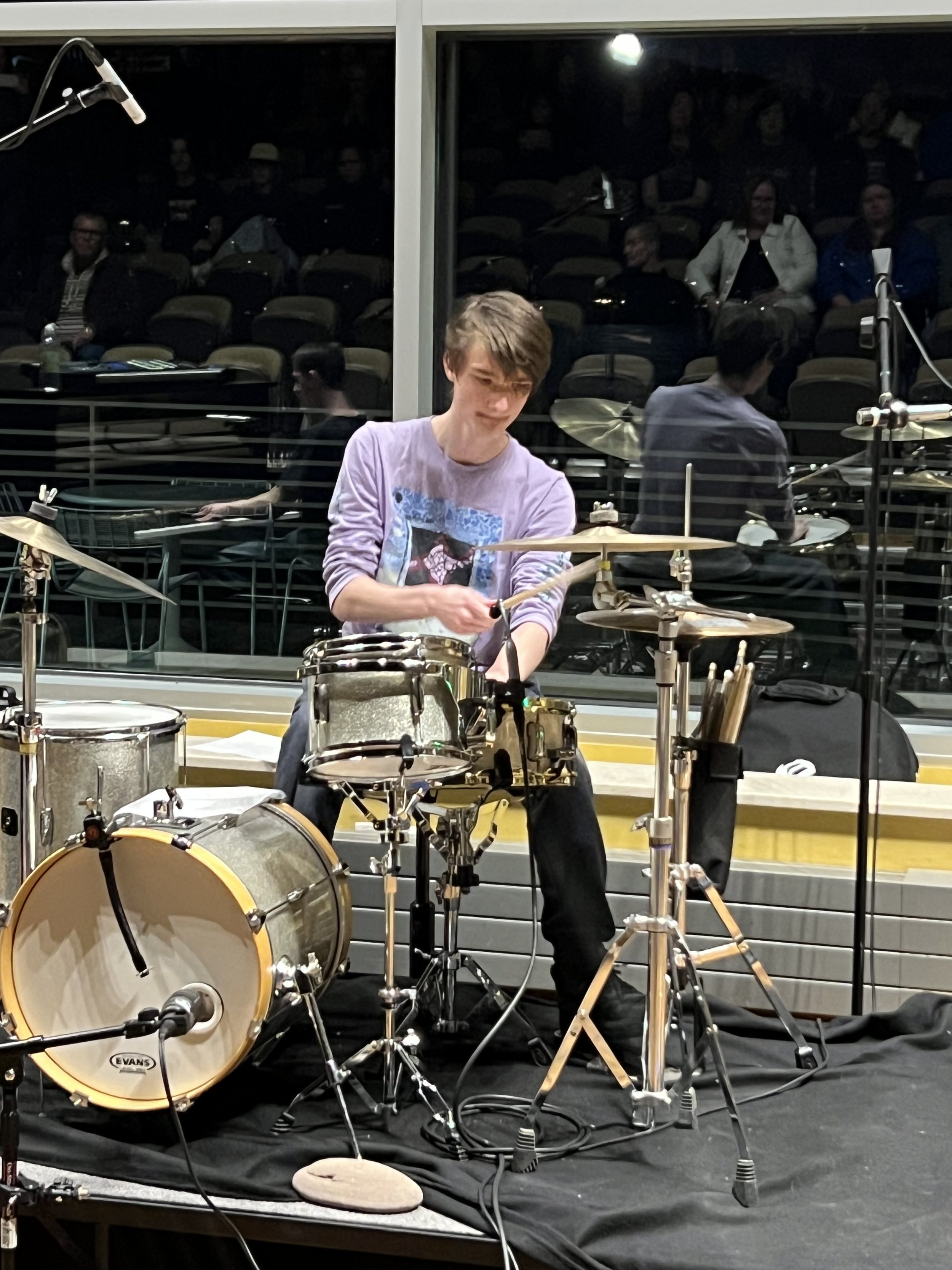 A drum set with cymbals and drums, with drumsticks resting on one of the drums.