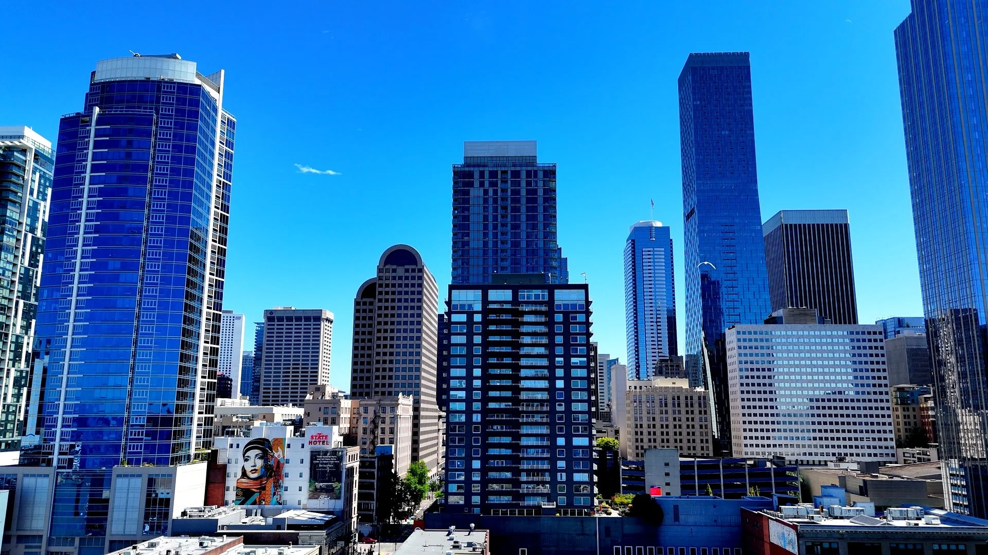 City skyline with tall modern skyscrapers and buildings against a bright blue sky.