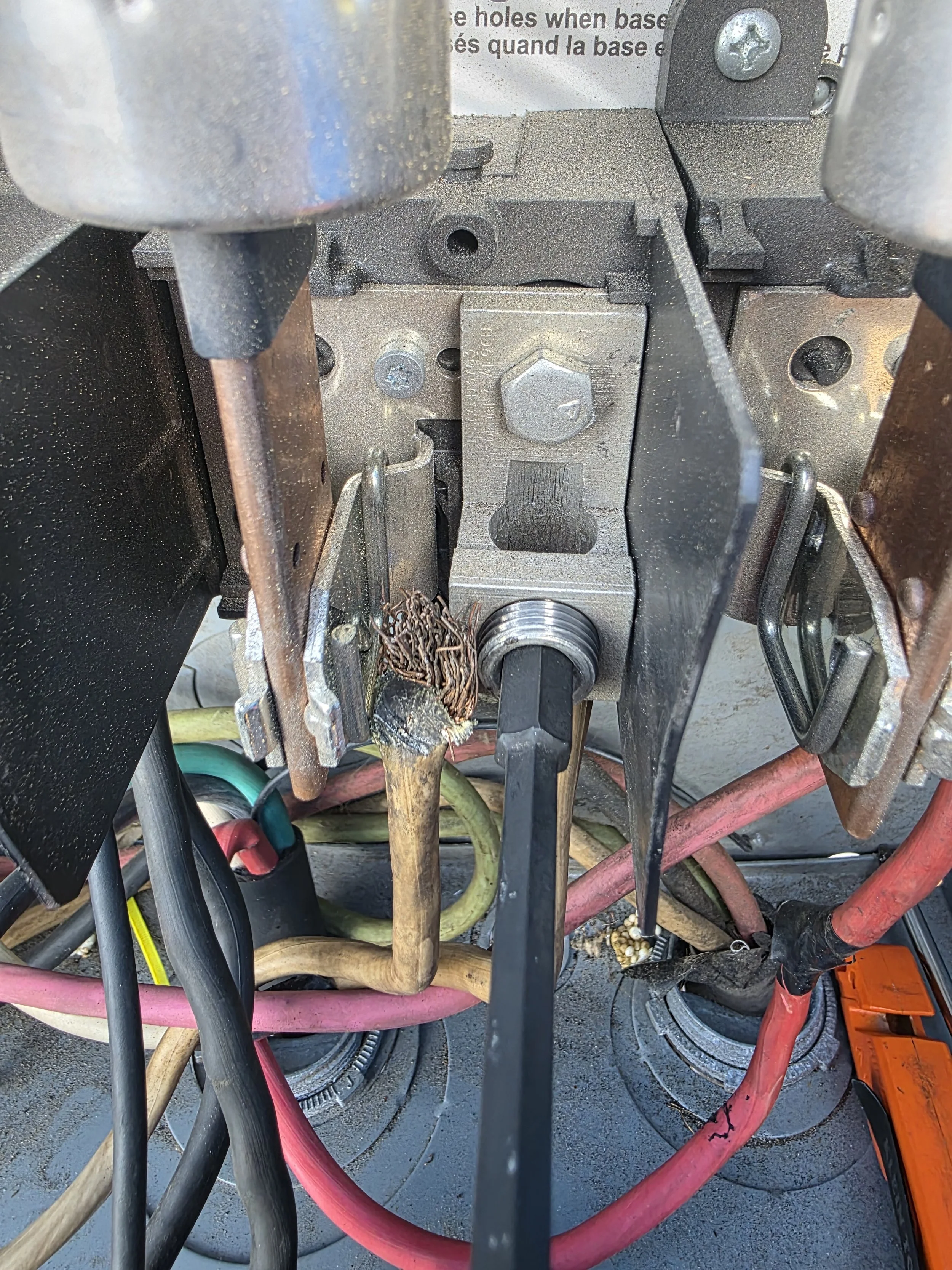 Close-up of an electrical or mechanical component with wires, screws, and metal parts on a workbench or industrial setting.