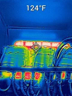 Thermal image of a vehicle's engine area showing heat distribution with bright spots indicating high temperatures, and the temperature reading of 124°F at the top.