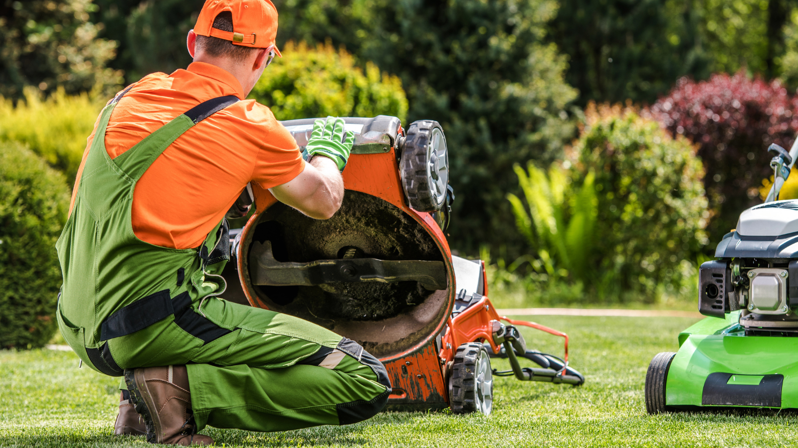 Lawn care worker cleaning a lawn mower in a garden.