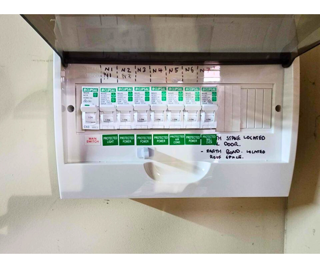 Electrical breaker panel with seven protected power switches, one main switch, and notes indicating utility areas with speaker located outside and earth bond attached to the roof space.