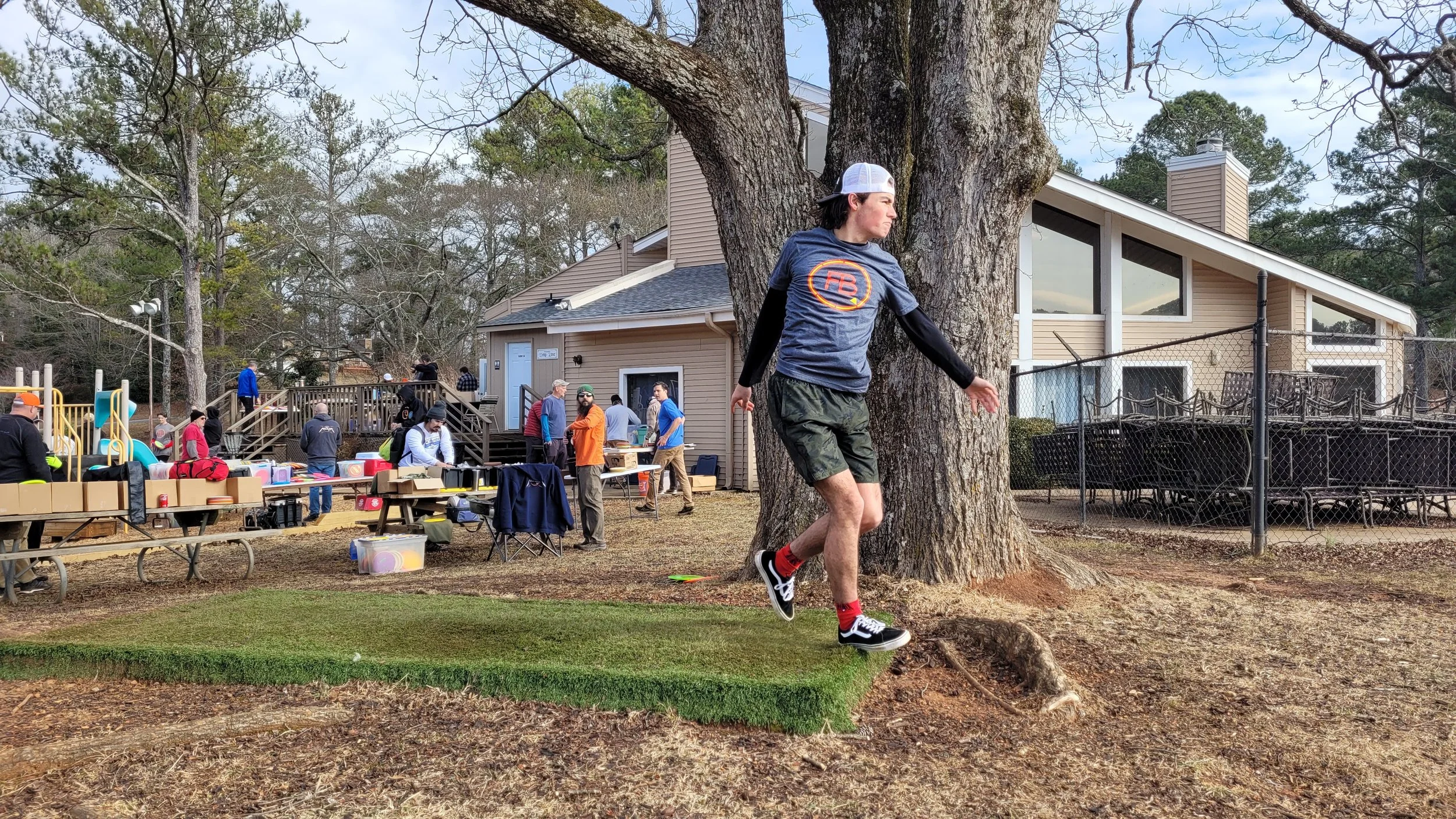 A young man launches a drive of Long #1.  There was a community swap meet happening.
