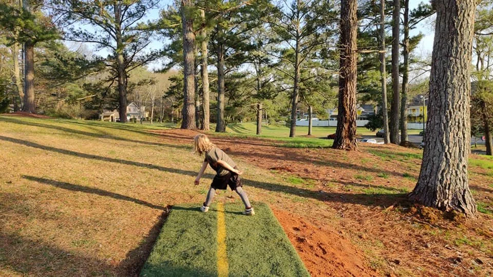 One of the young course builders throws a shot on hole 18.