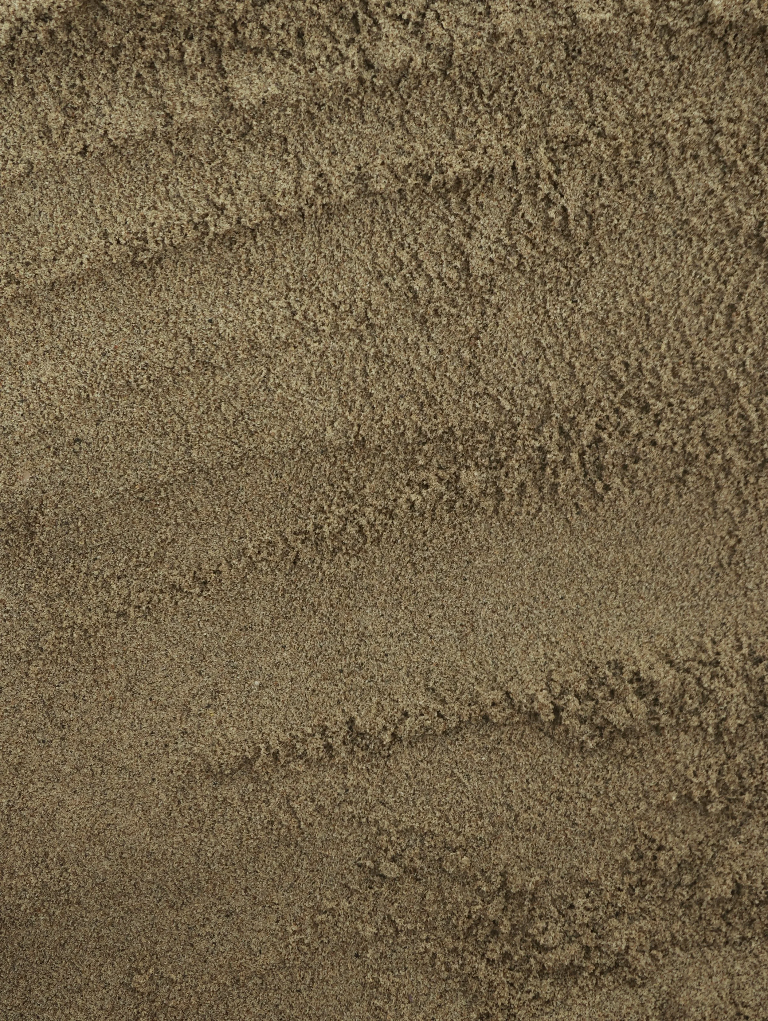 Close-up of brown sand with small ridges and textures.