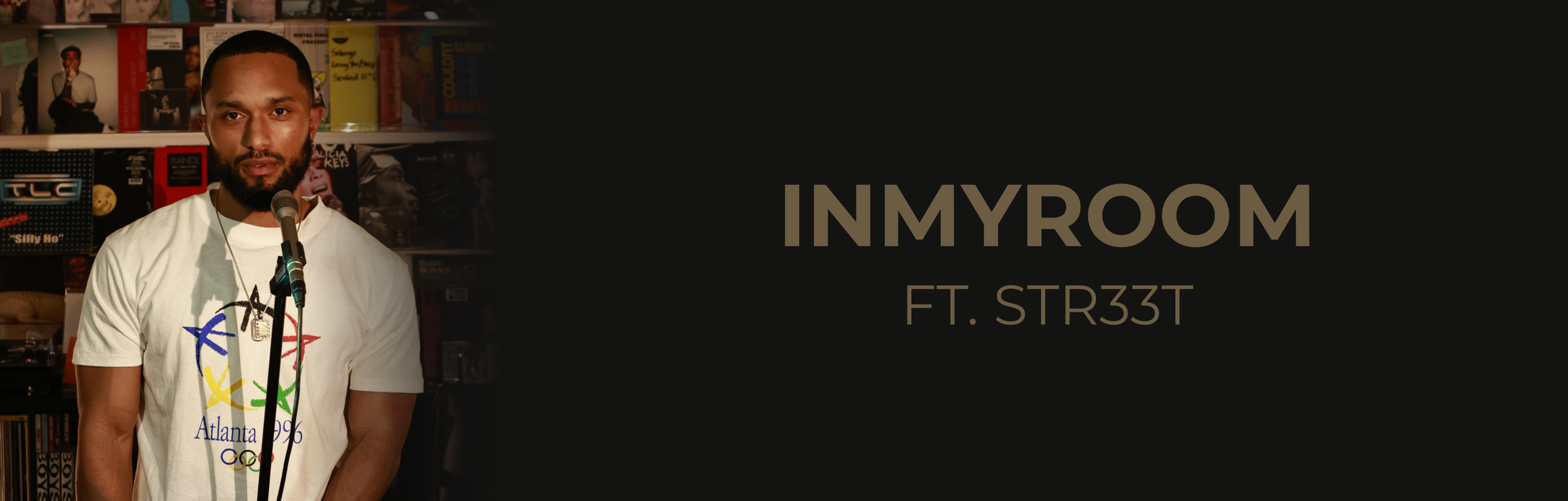 A man with a beard wearing a white t-shirt with colorful graphics and a necklace, standing in front of a microphone in a record store with shelves of vinyl records in the background. On the right side, black background with the text 'IN MY ROOM FT. STR33T'.