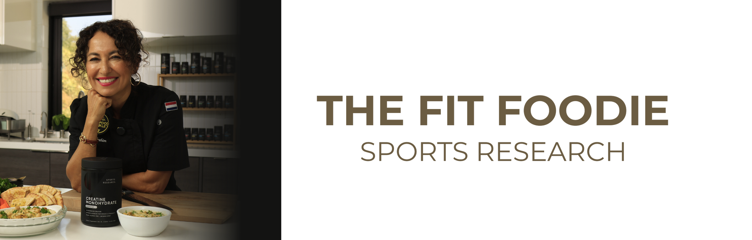 A woman smiling with curly hair, wearing a black chef's coat with a Netherlands flag patch, sitting at a kitchen counter with healthy food dishes and a black sports supplement container labeled 'Creatine Monohydrate'.