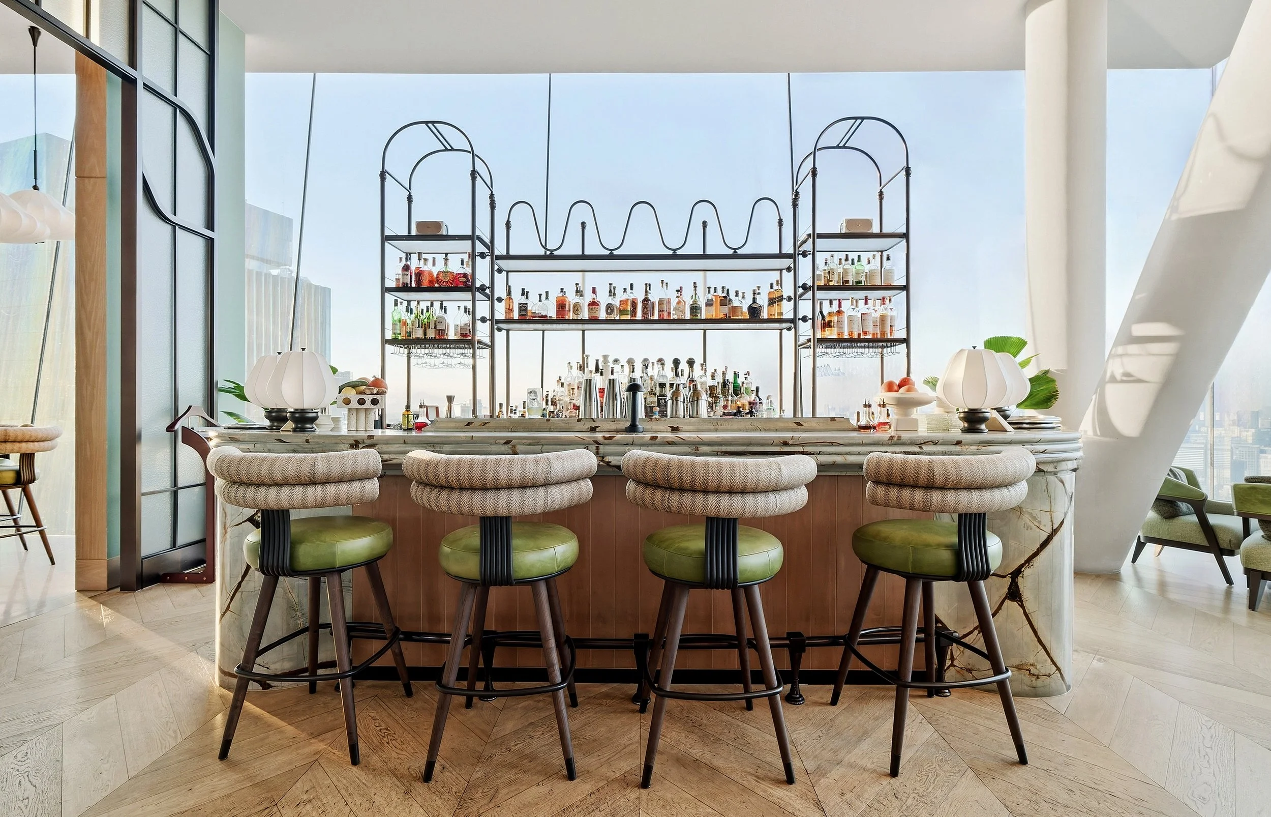 Luxury rooftop bar overlooking panoramic views of an Asian city skyline before sunset.