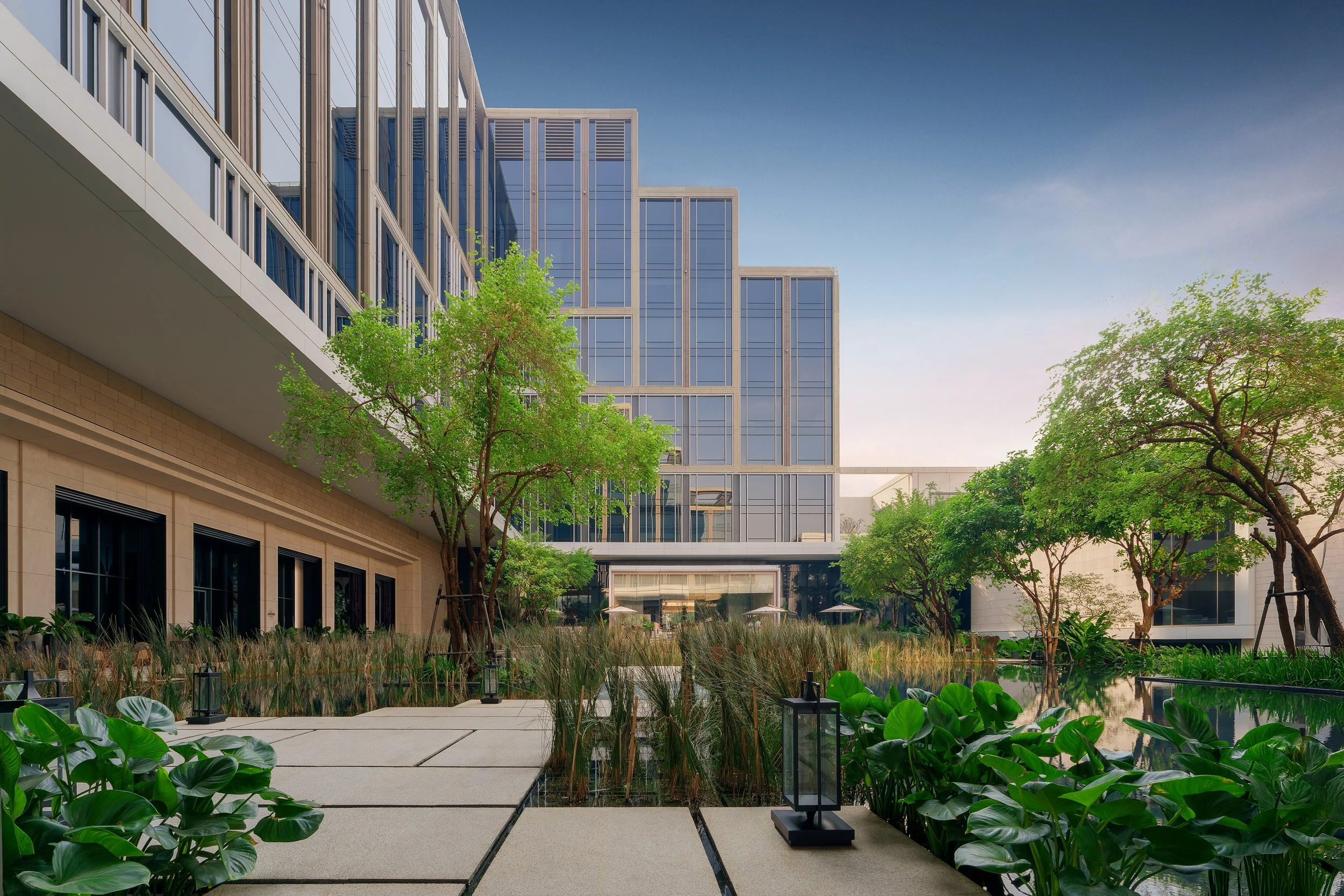 Luxury Hotel common areas, surrounded by landscaped greenery, water features, and pathways near Chao-Praya river, Bangkok.