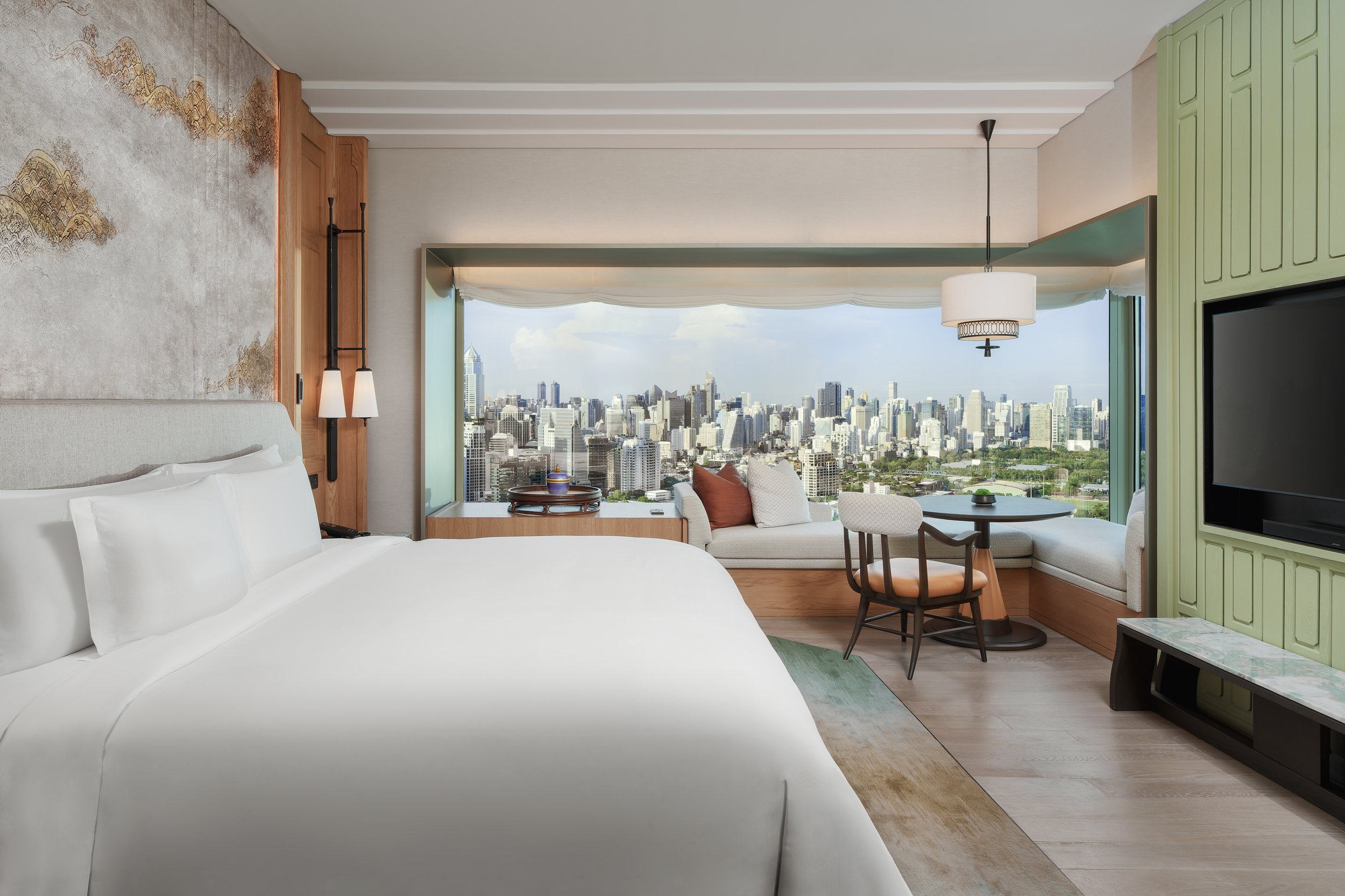 Luxurious hotel room with upscale furniture, a day bed by the panoramic window and stunning views of the city in Bangkok.