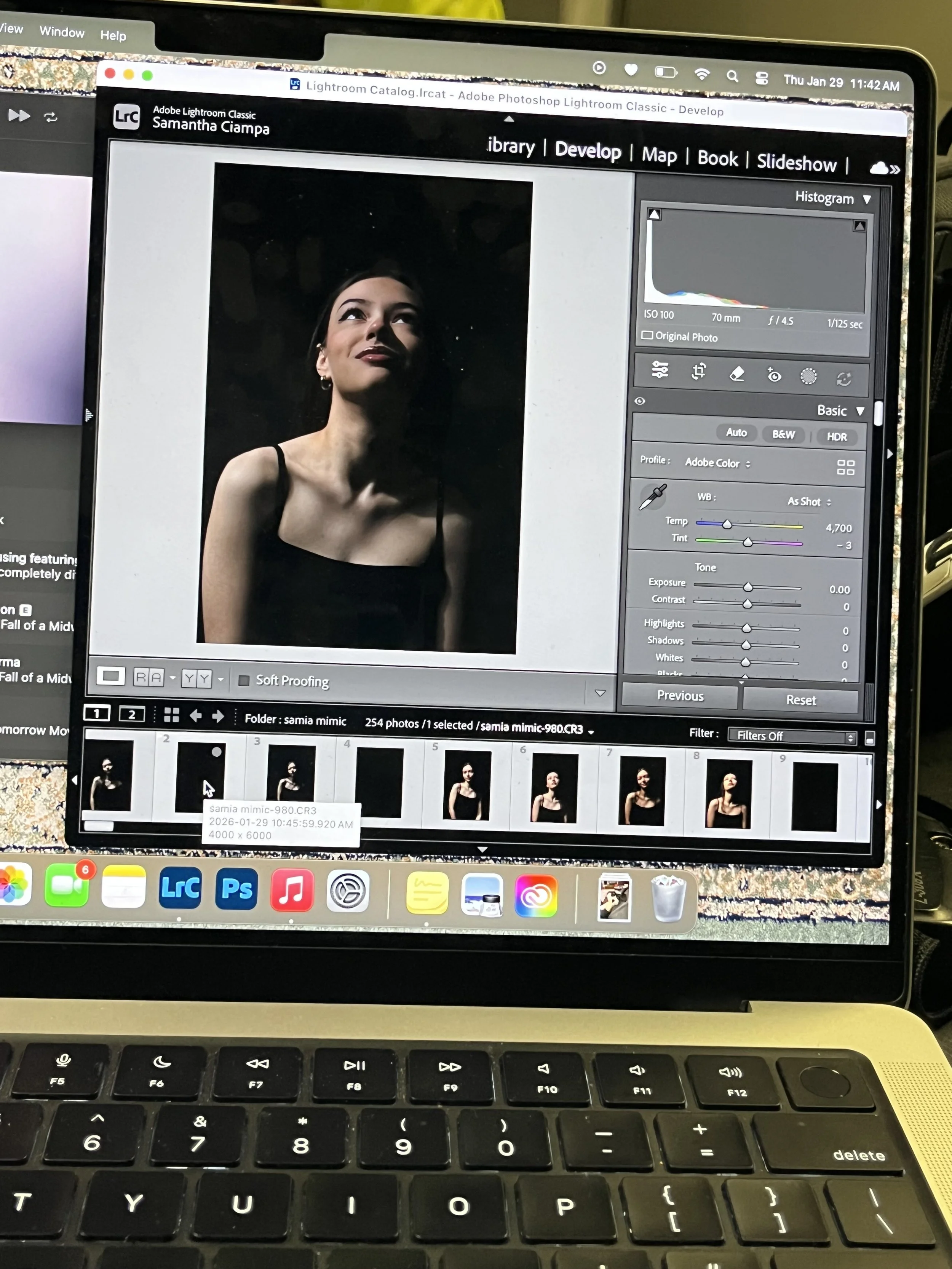 Laptop screen displaying a photo editing software with an image of a woman with short dark hair wearing a black top, looking upward, with thumbnail images of different pose variations of the woman below.
