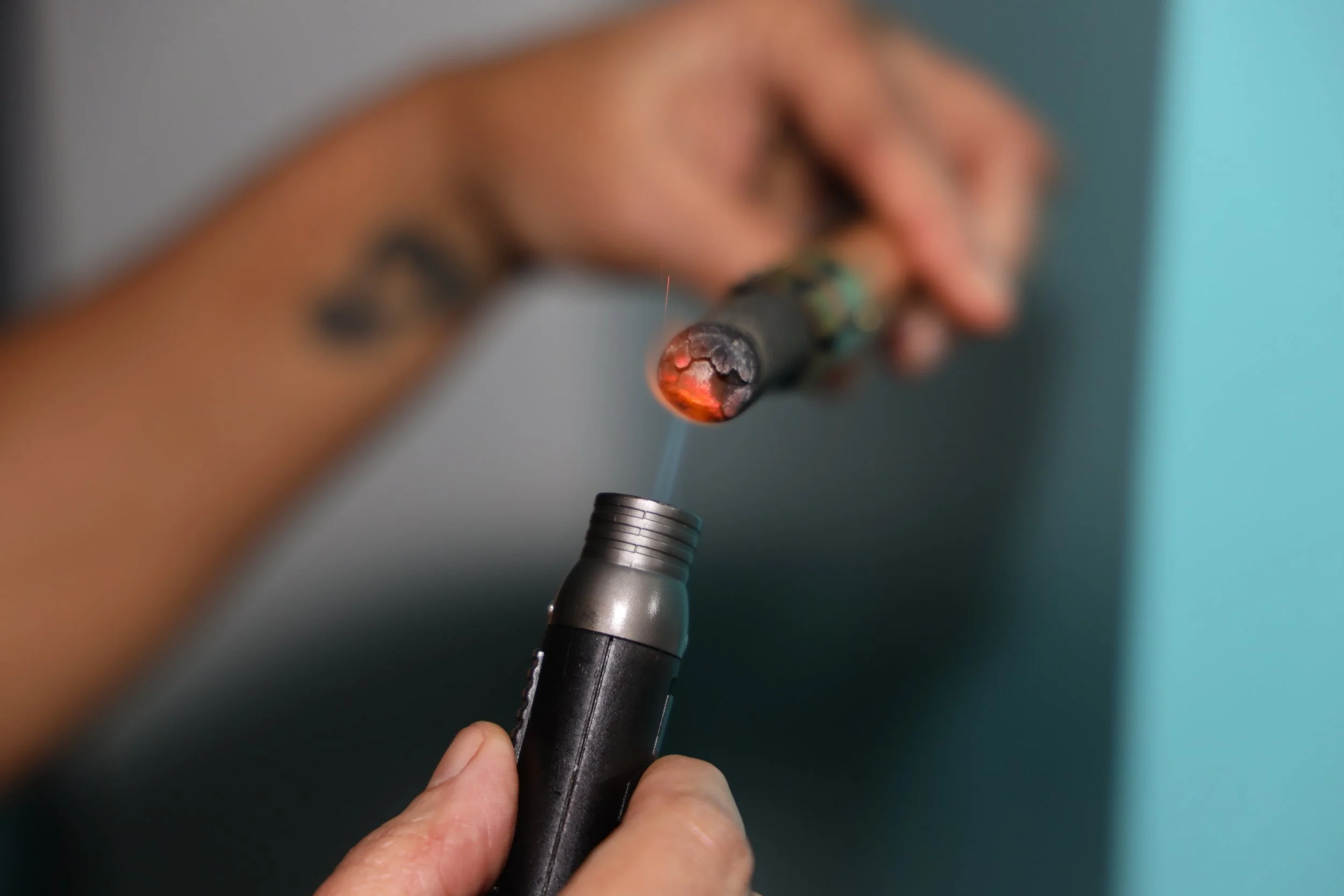Close-up of a hand holding a soldering iron with a glowing tip, positioned near a metallic socket or component.