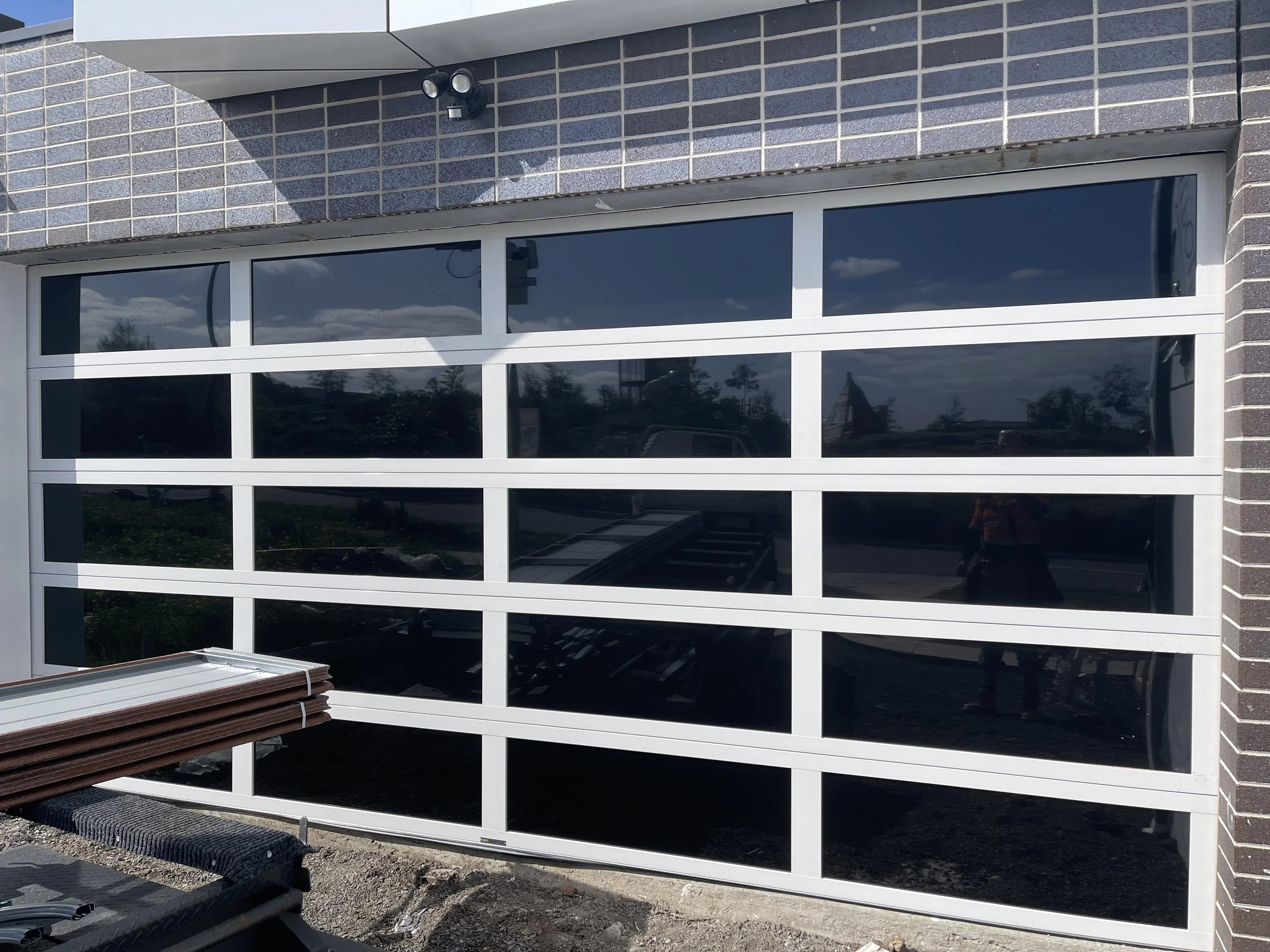 Newly installed black glass sectional garage door with white framing 