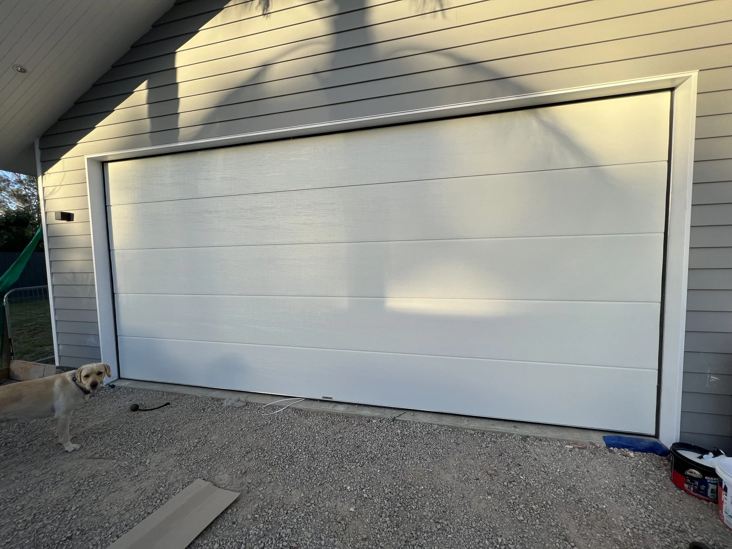 A white garage door on a house with beige siding repair