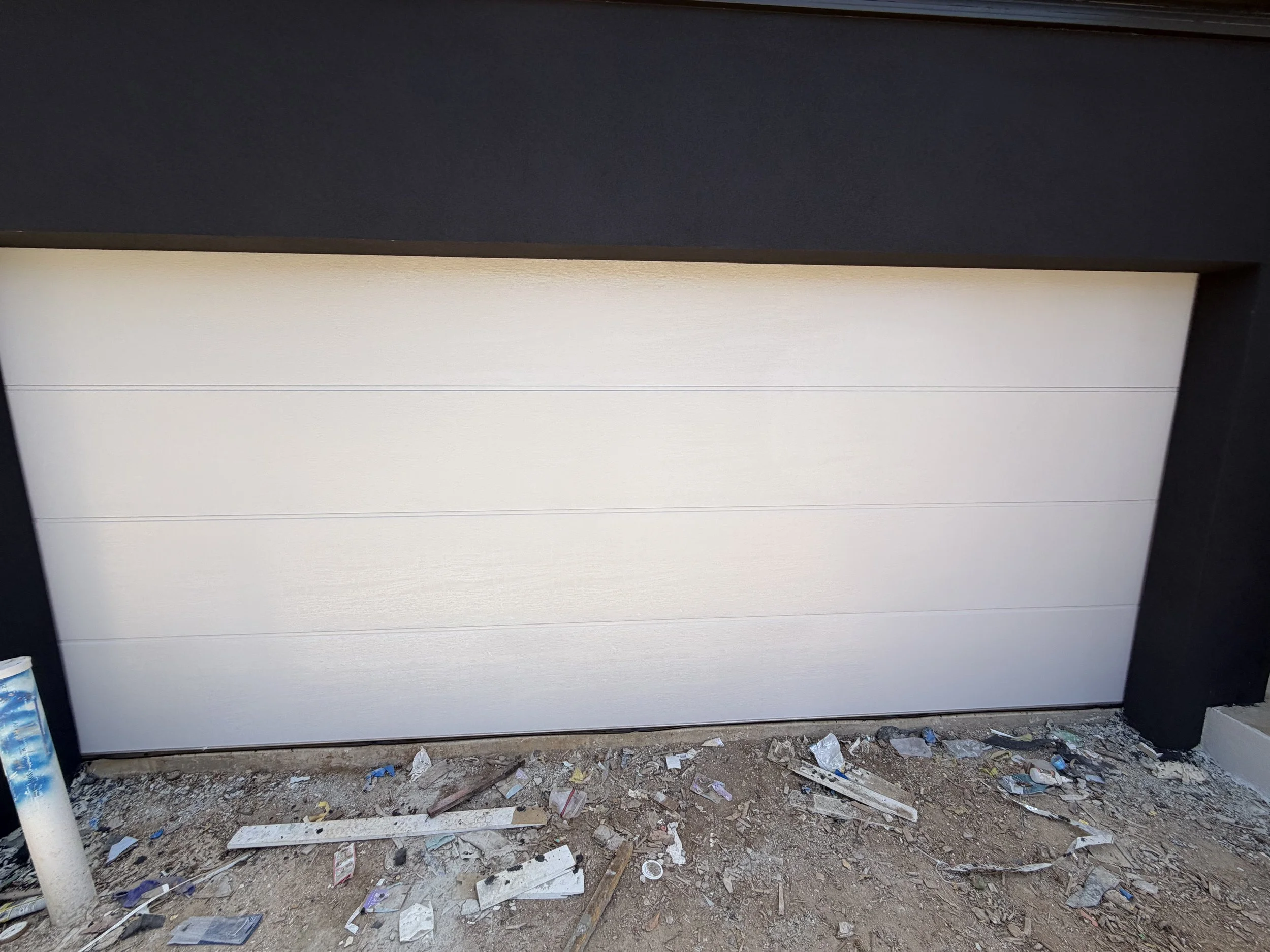 A partially installed white garage door with black framing