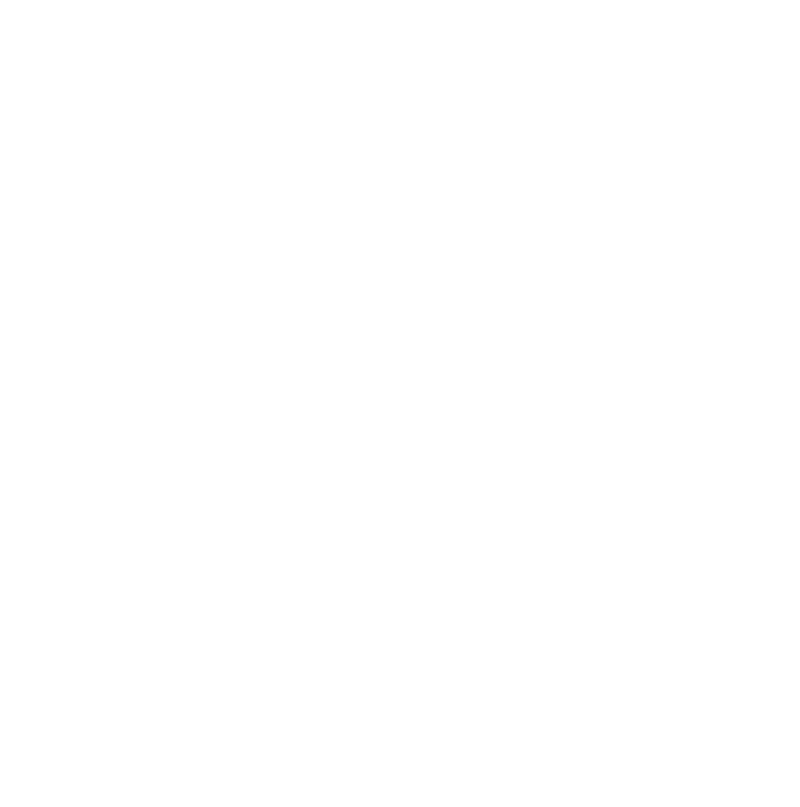 A person with curly hair and glasses taking a selfie in a mirror, smiling and wearing a gray jacket.