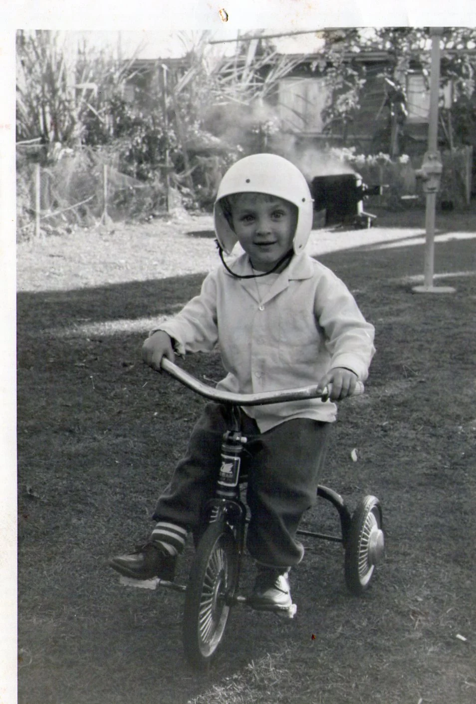 Black and white photo of Will Marx as a little boy riding his tricycle with helmet