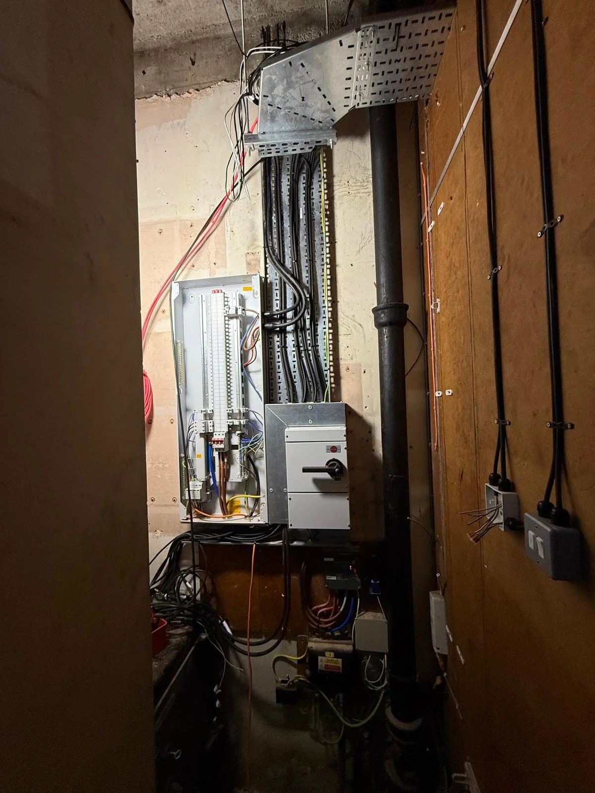 Electrical panel with wiring and pipes in a utility room