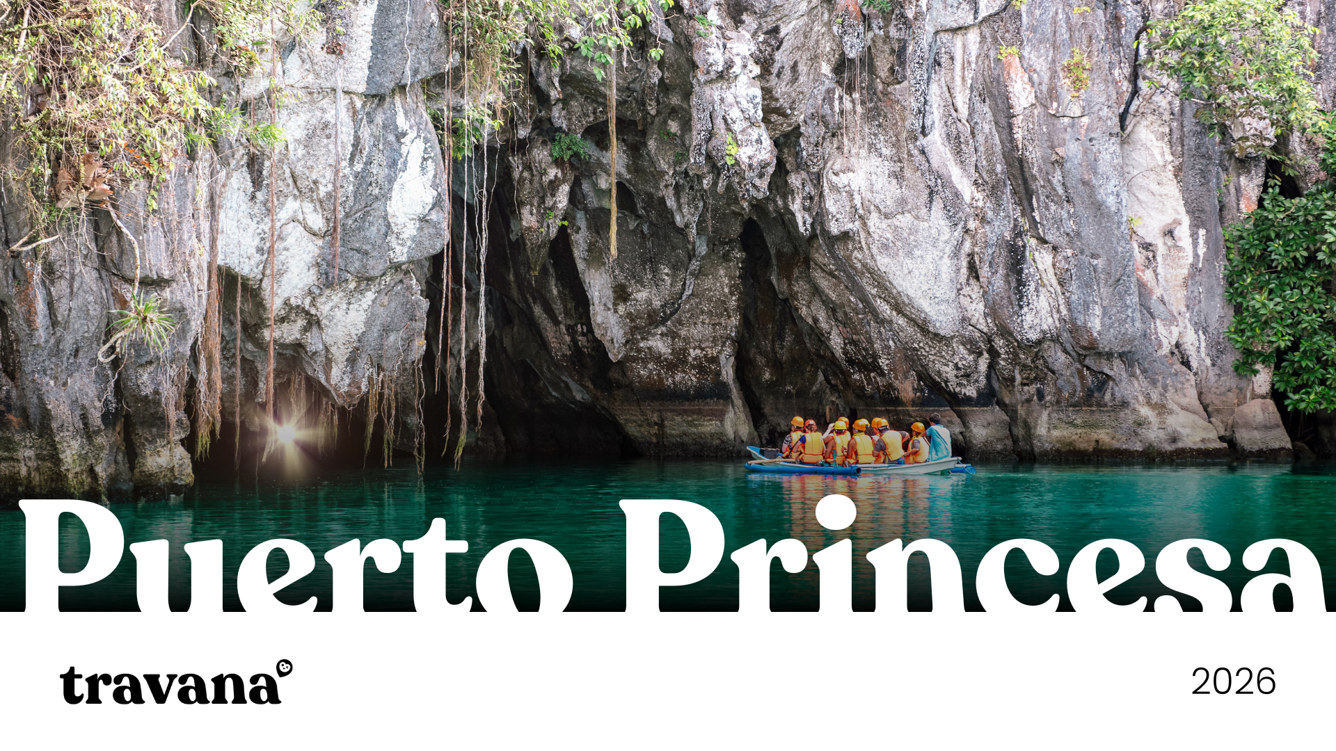 Group of people wearing orange life jackets and helmets on a boat in a turquoise water cove with large rocky cliffs and lush green vegetation in Puerto Princesa, Philippines.