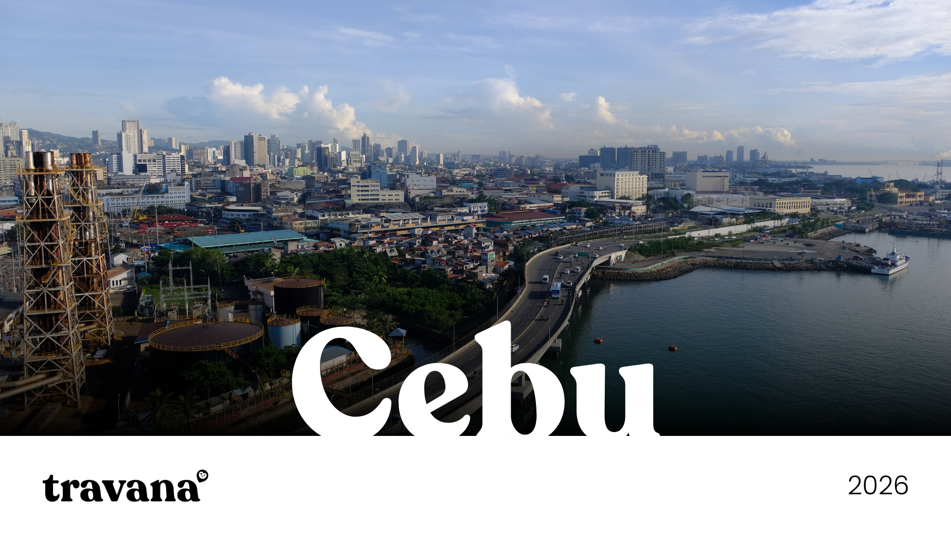 Aerial view of Cebu city skyline with high-rise buildings, harbor, and a curved road along the water, under partly cloudy sky.