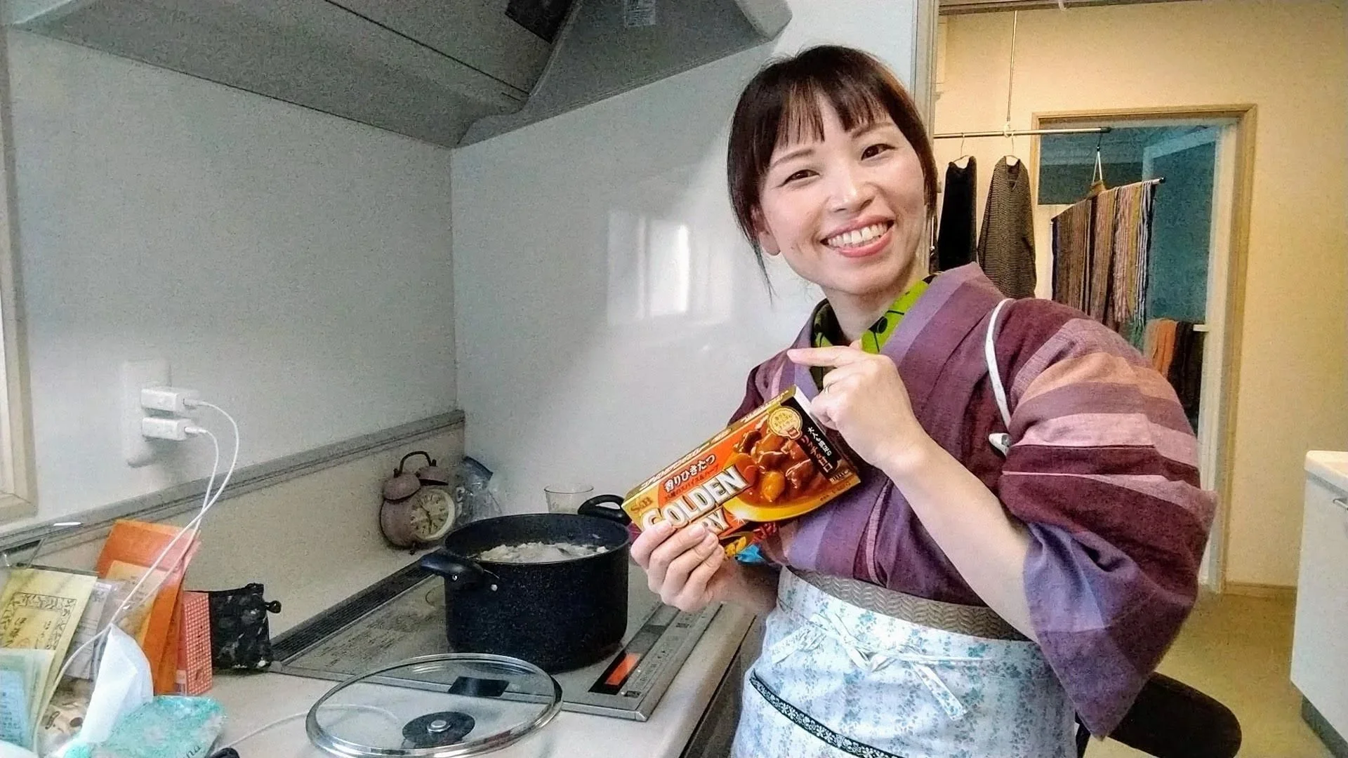 料理を作る女性がキッチンで笑顔でポーズをとっている。