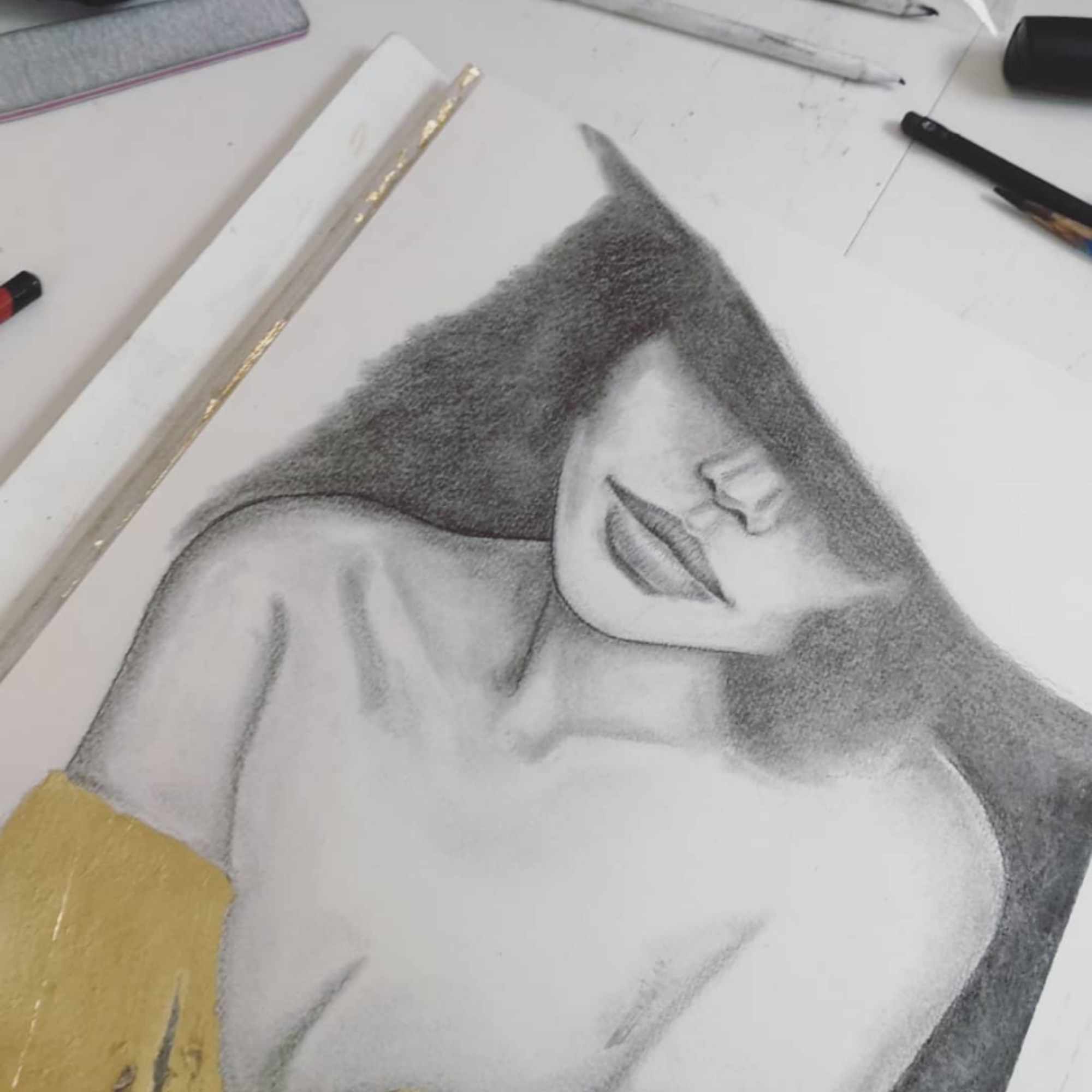 A detailed graphite pencil drawing of a woman with bangs partially covering her face, showing her lips, nose, and shoulder, with a gold-colored sleeve on her arm.