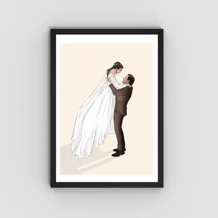 A wedding photo of a groom lifting a bride in a white wedding dress, framed in black.