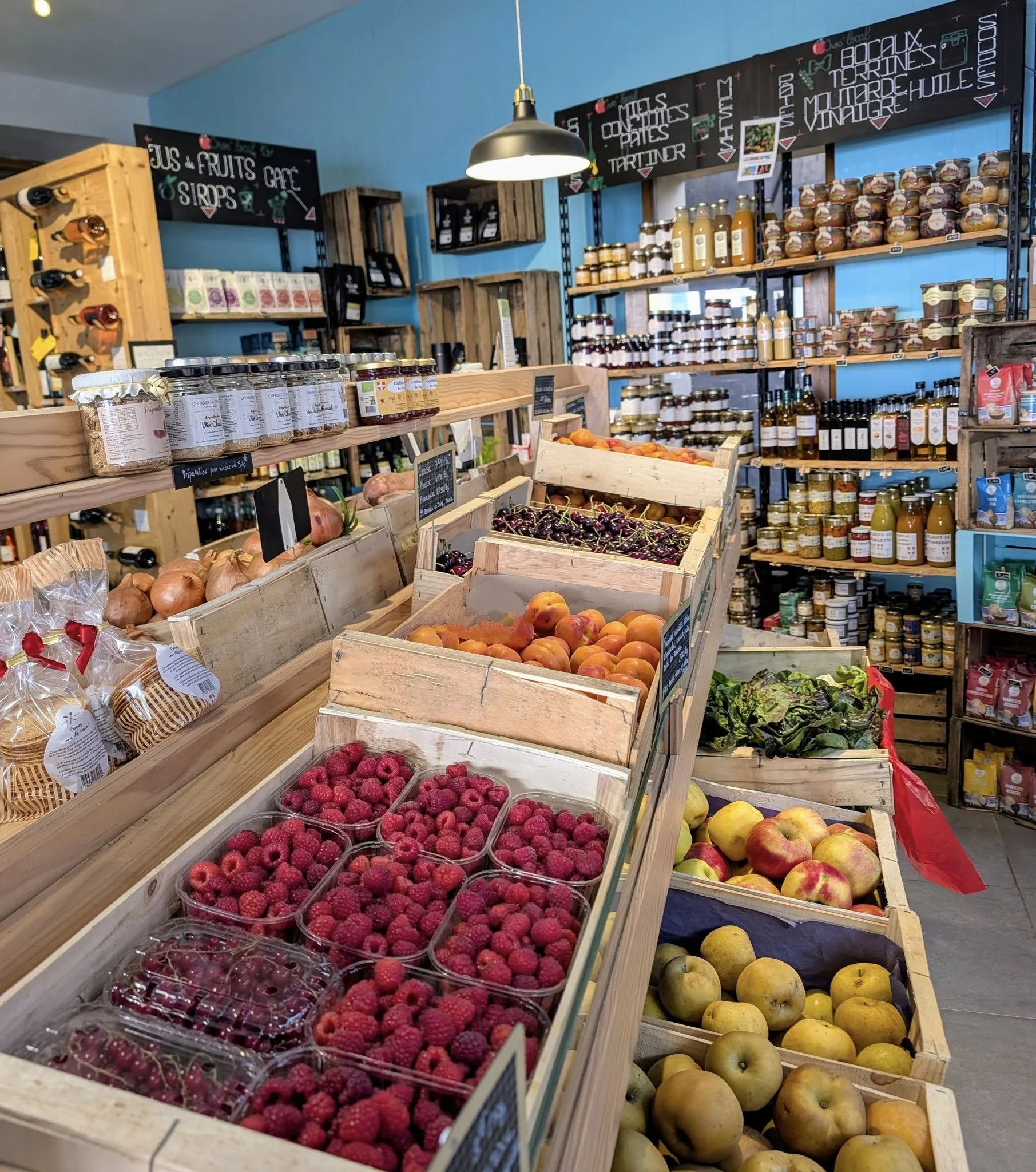Fruits et produits frais dans une épicerie, avec des fruits rouges, pommes, et autres produits en distribution.