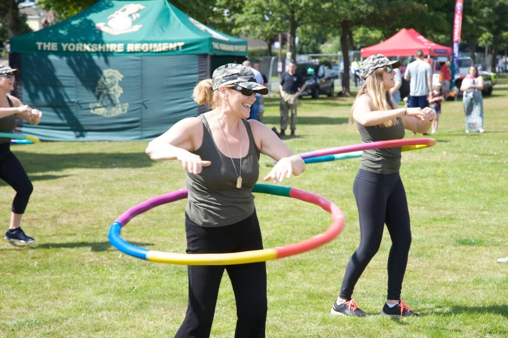 Ladies hula-hooping in an exercise class outside.