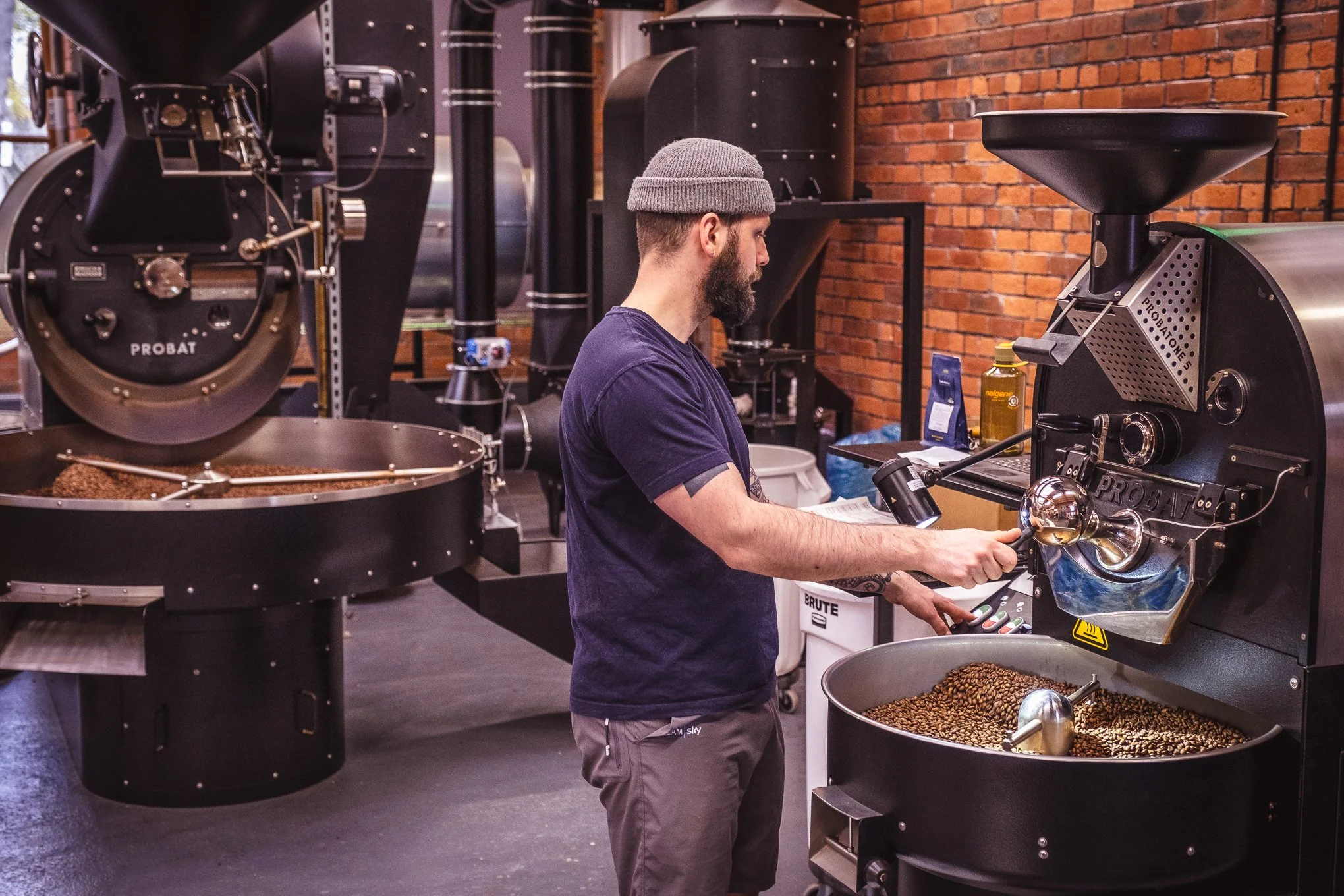 A member of staff handling coffee beans at Dark Woods Coffee roastery.