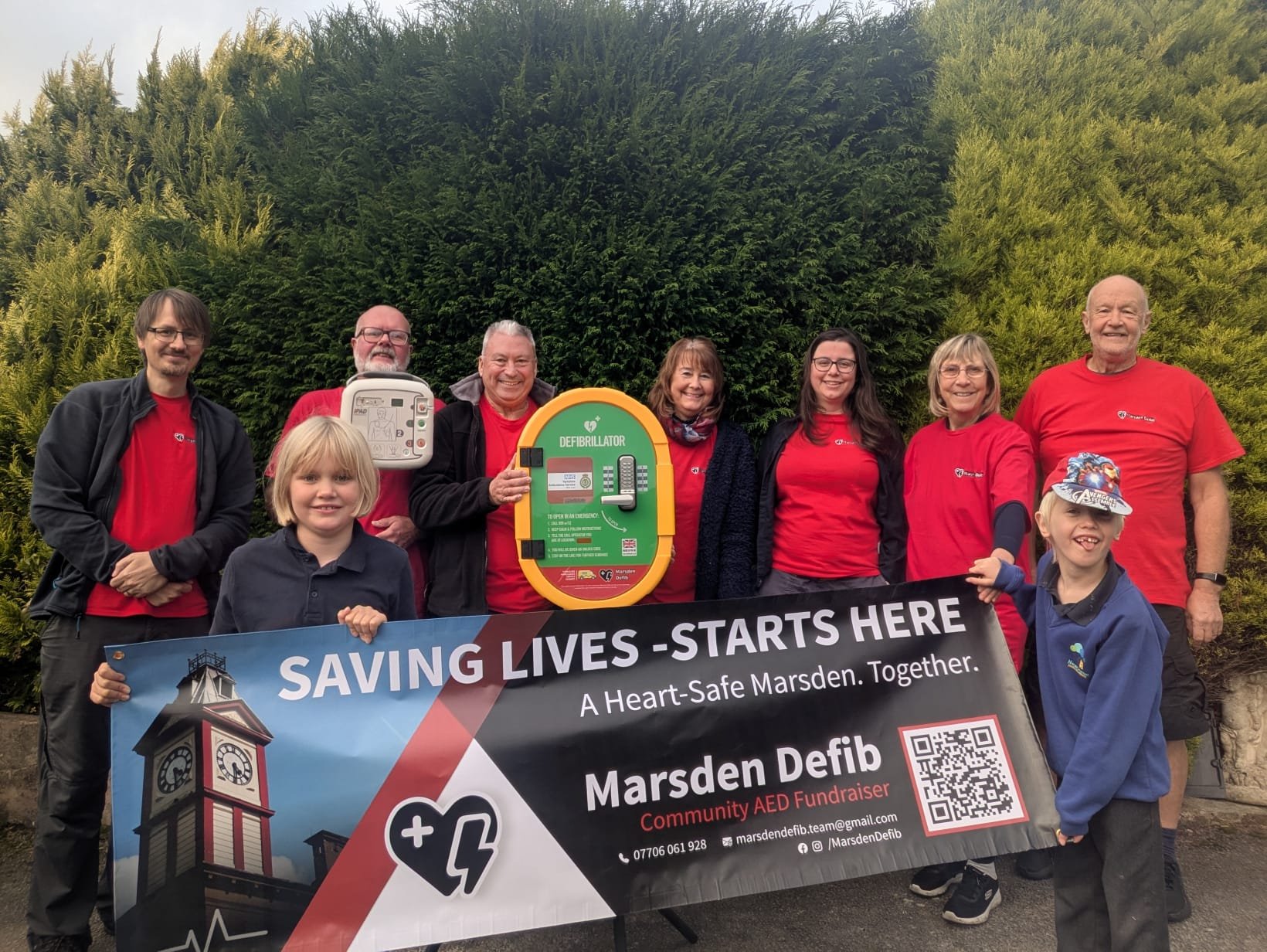 Members of the Marsden Defib Association with an advertising banner and defibrillator.