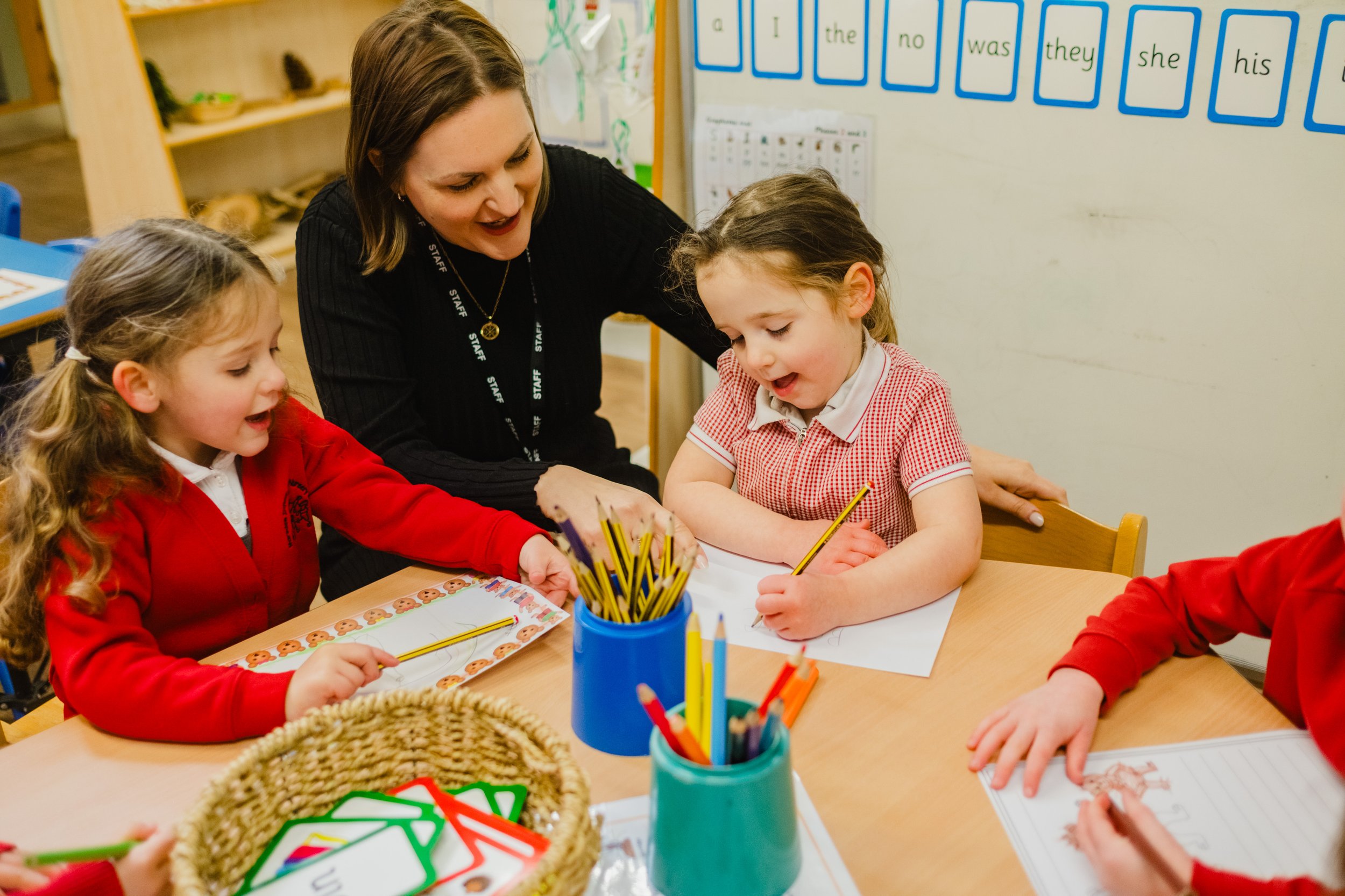 A staff member helping students at Marsden Infant and Nursery School, West Yorkshire.