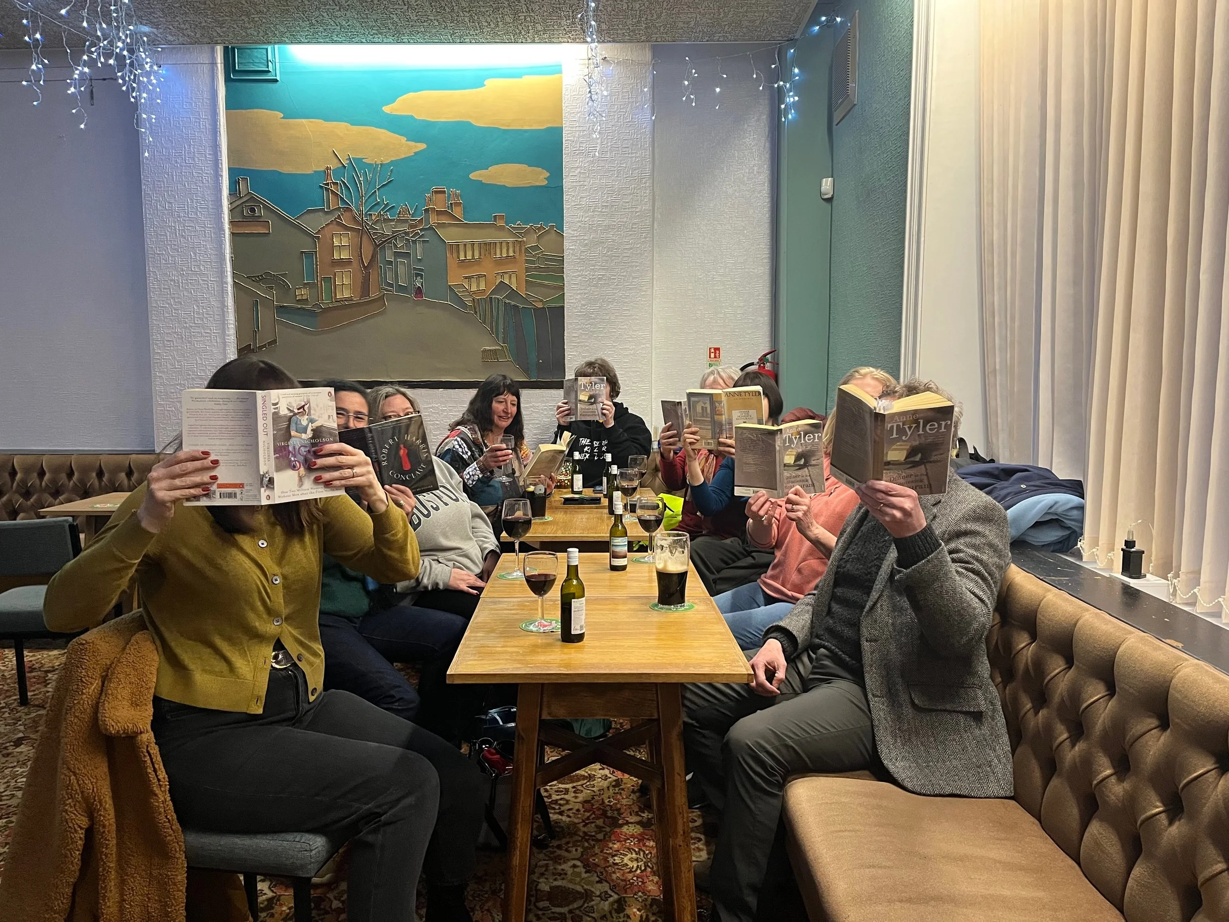 The members of Marsden Evening Book Club, West Yorkshire, holding books in front of their faces.